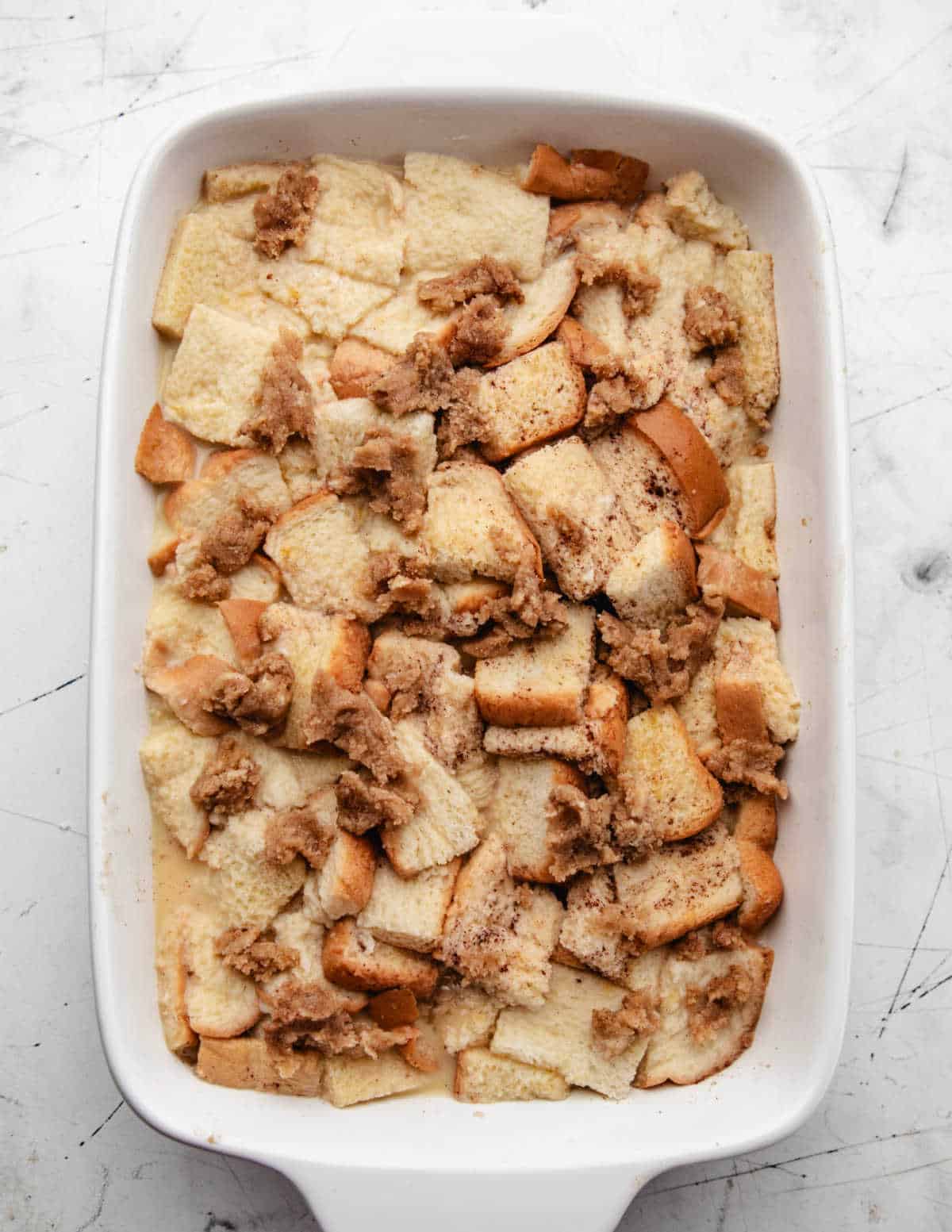 Pieces of brown sugar topping over the top of an unbaked French toast casserole. 