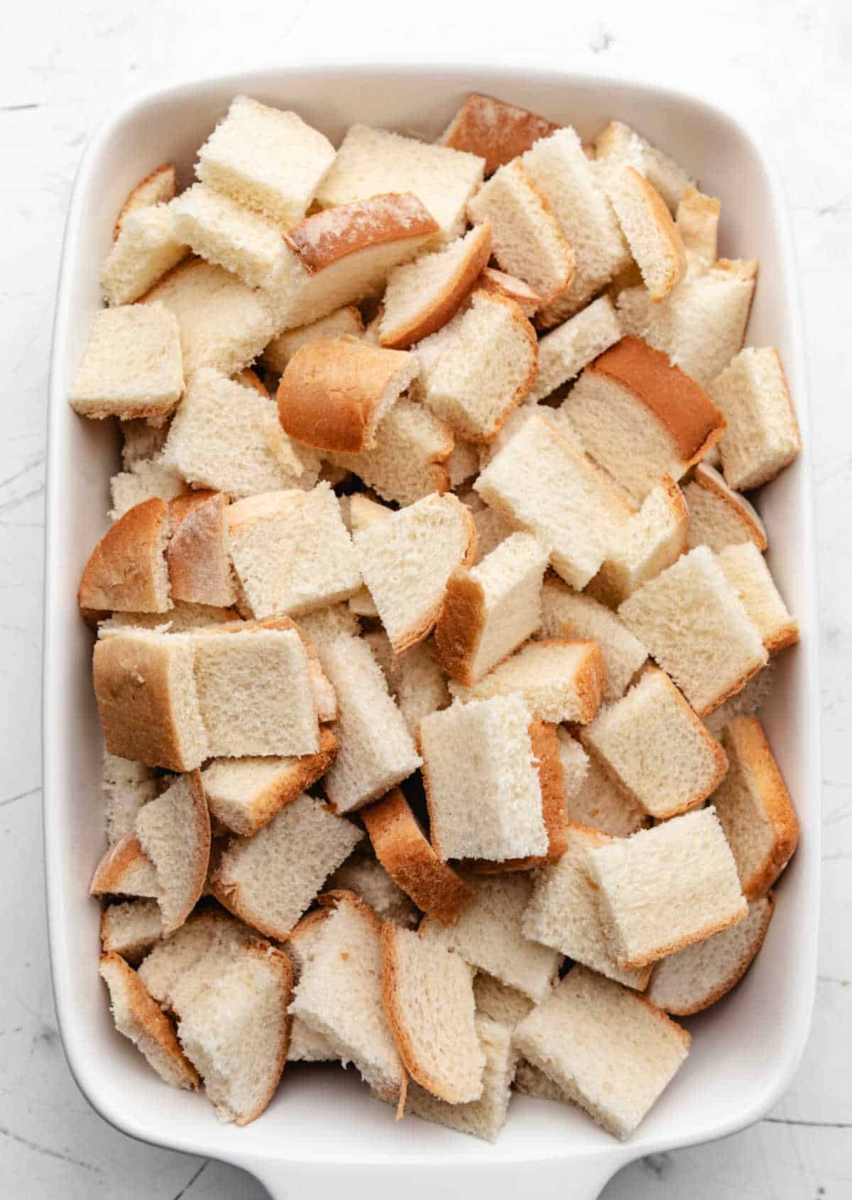 Cubed white bread in a white baking dish.