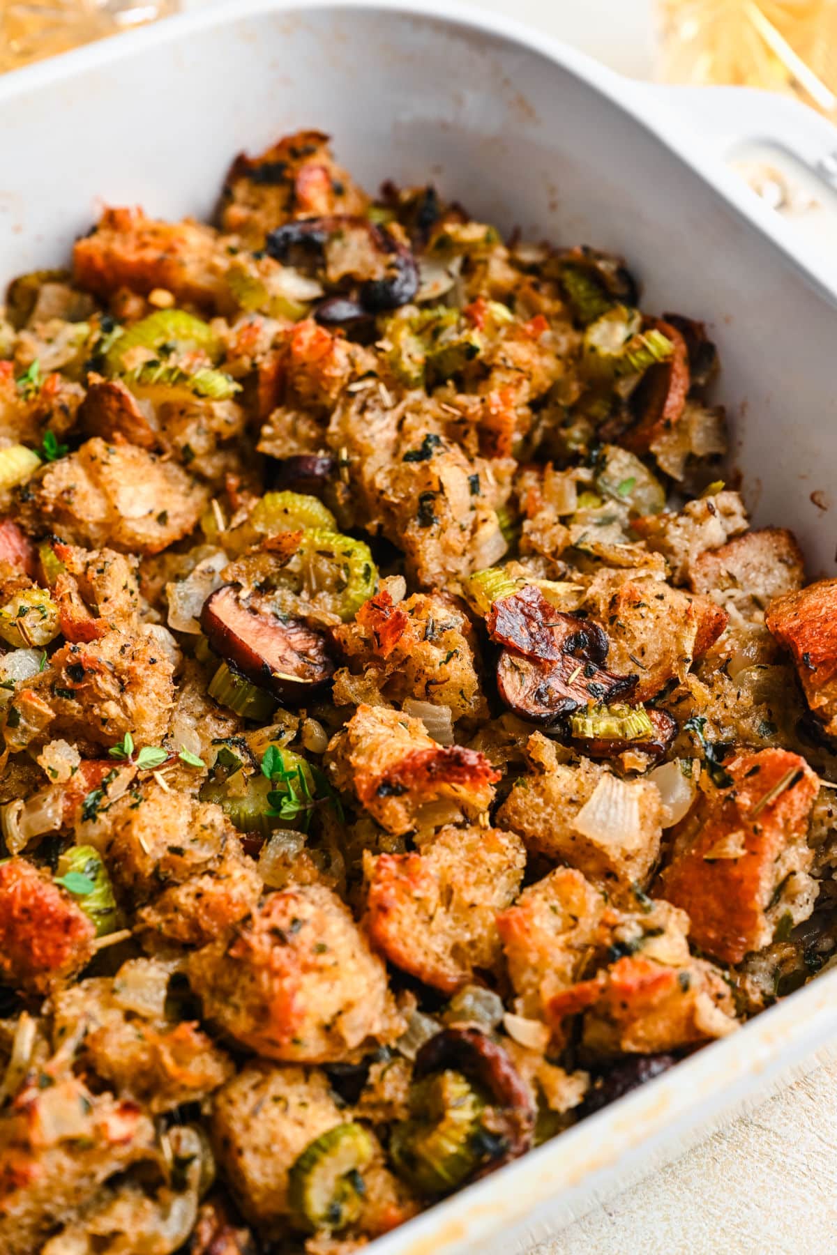 Close up photo of a pan of homemade stuffing in a white baking dish.