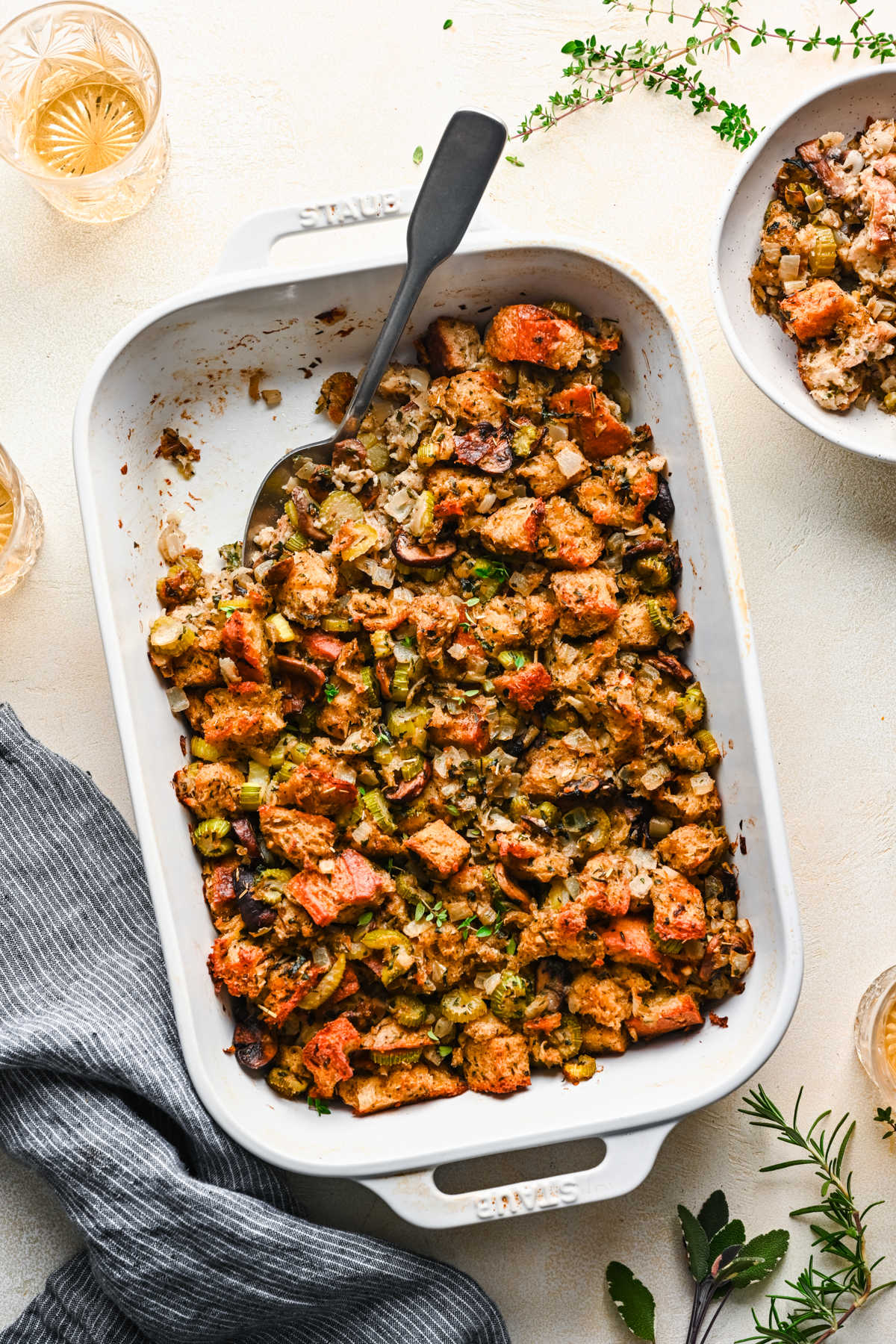 A white dish of baked Thanksgiving dressing with a scoop missing.