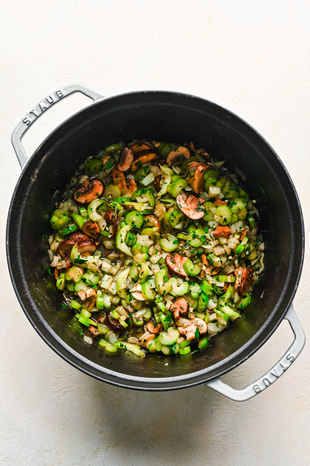 Celery onion mushrooms and garlic sautéing in a pot.