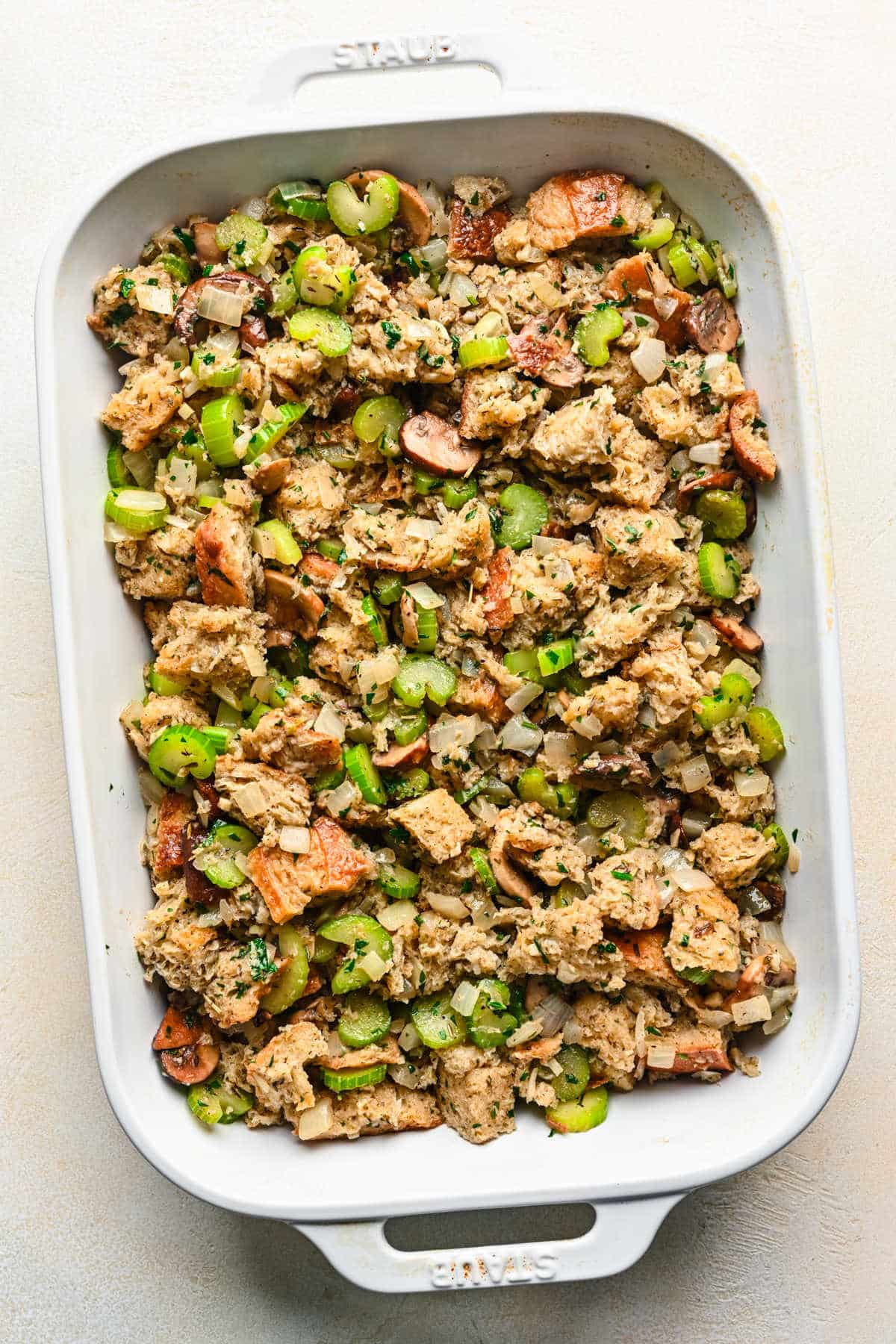 Unbaked stuffing in a white baking dish.