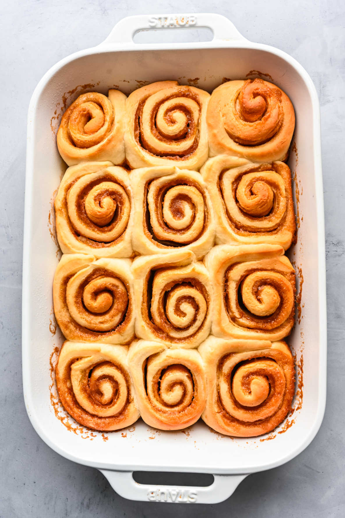 Baked maple cinnamon rolls in a white baking pan.