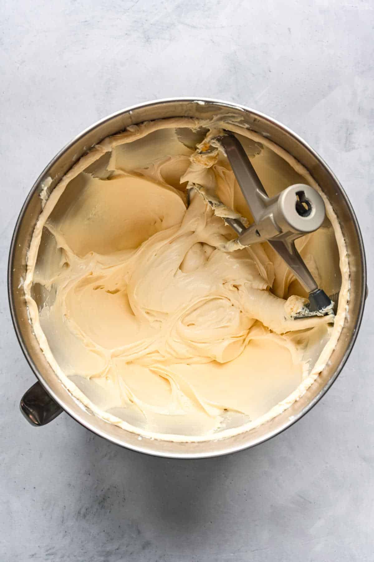 Maple cinnamon roll frosting in a silver mixing bowl.