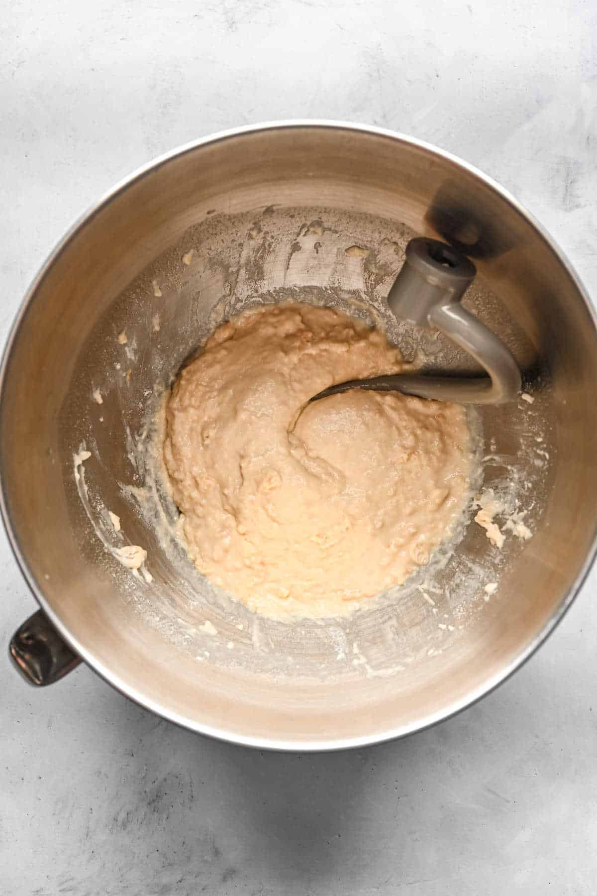 Yeast mixture and milk mixture mixed in a silver mixing bowl. 