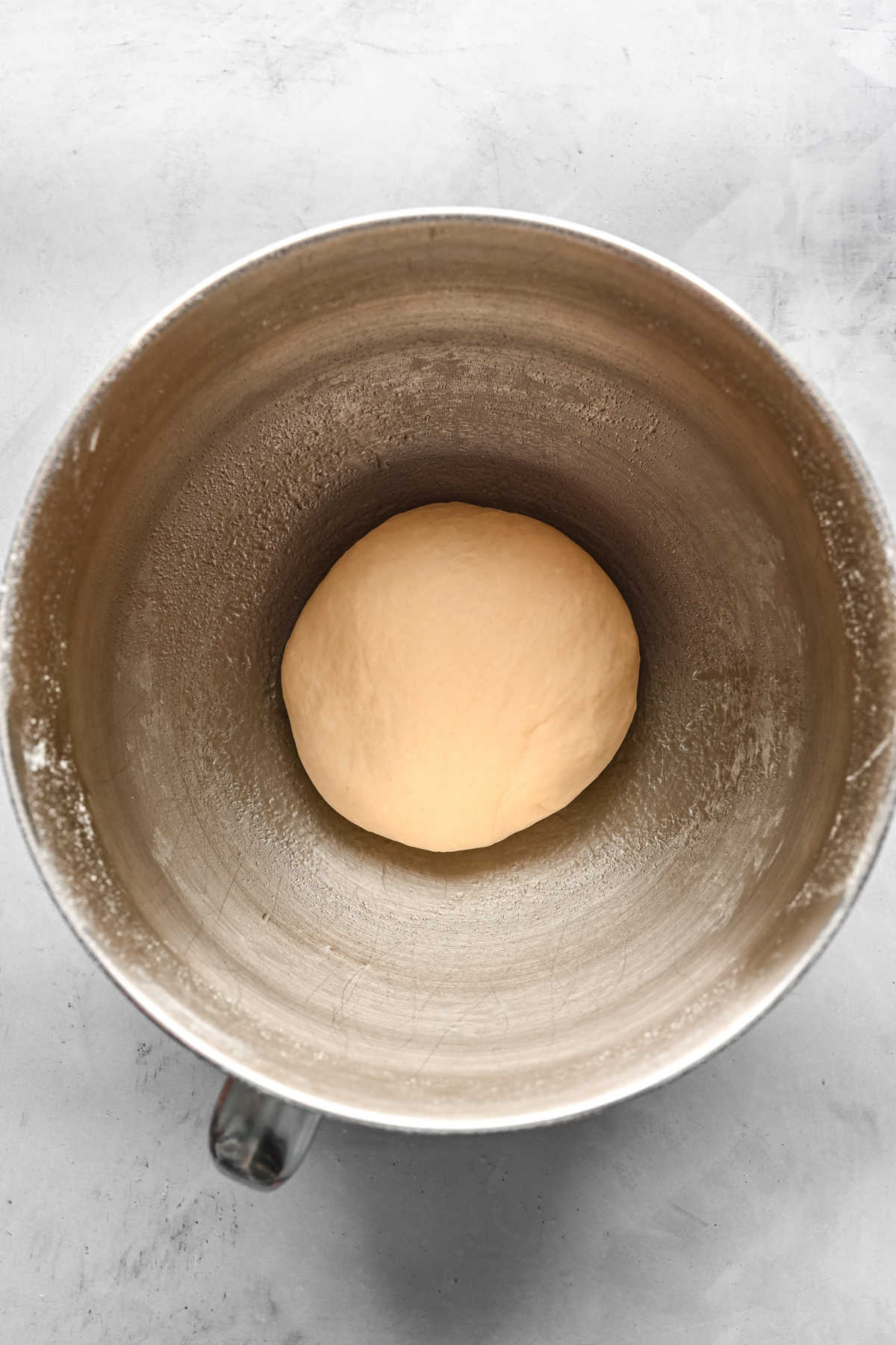 Maple cinnamon roll dough in a silver mixing bowl. 