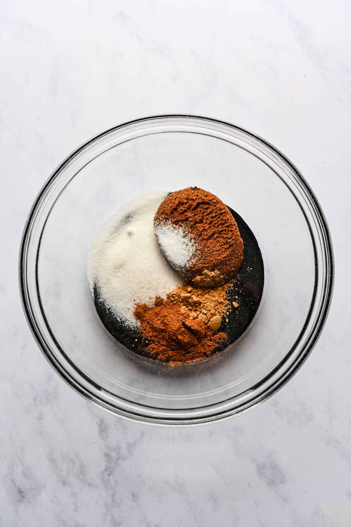 Molasses and sugar in a glass mixing bowl.