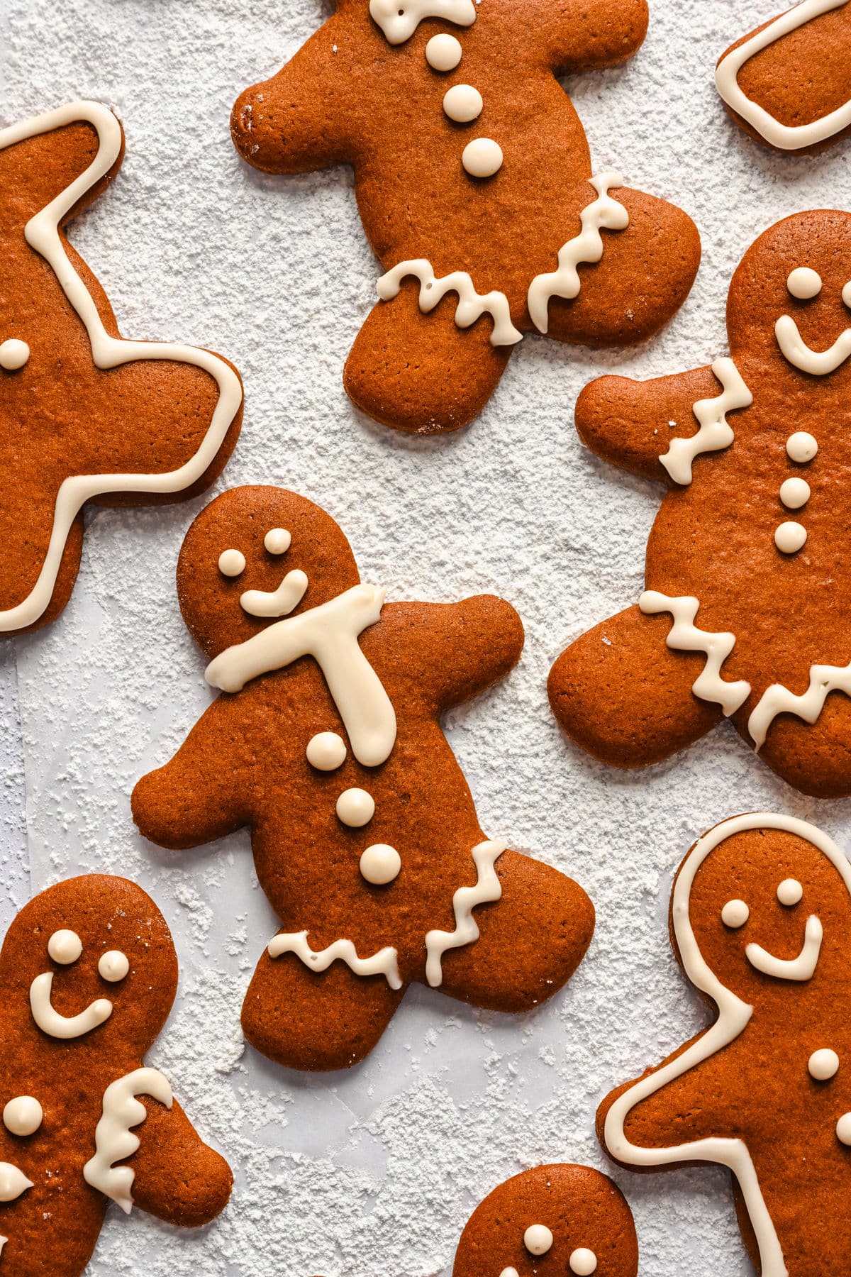 Decorated gingerbread men on a powdered sugar background. 