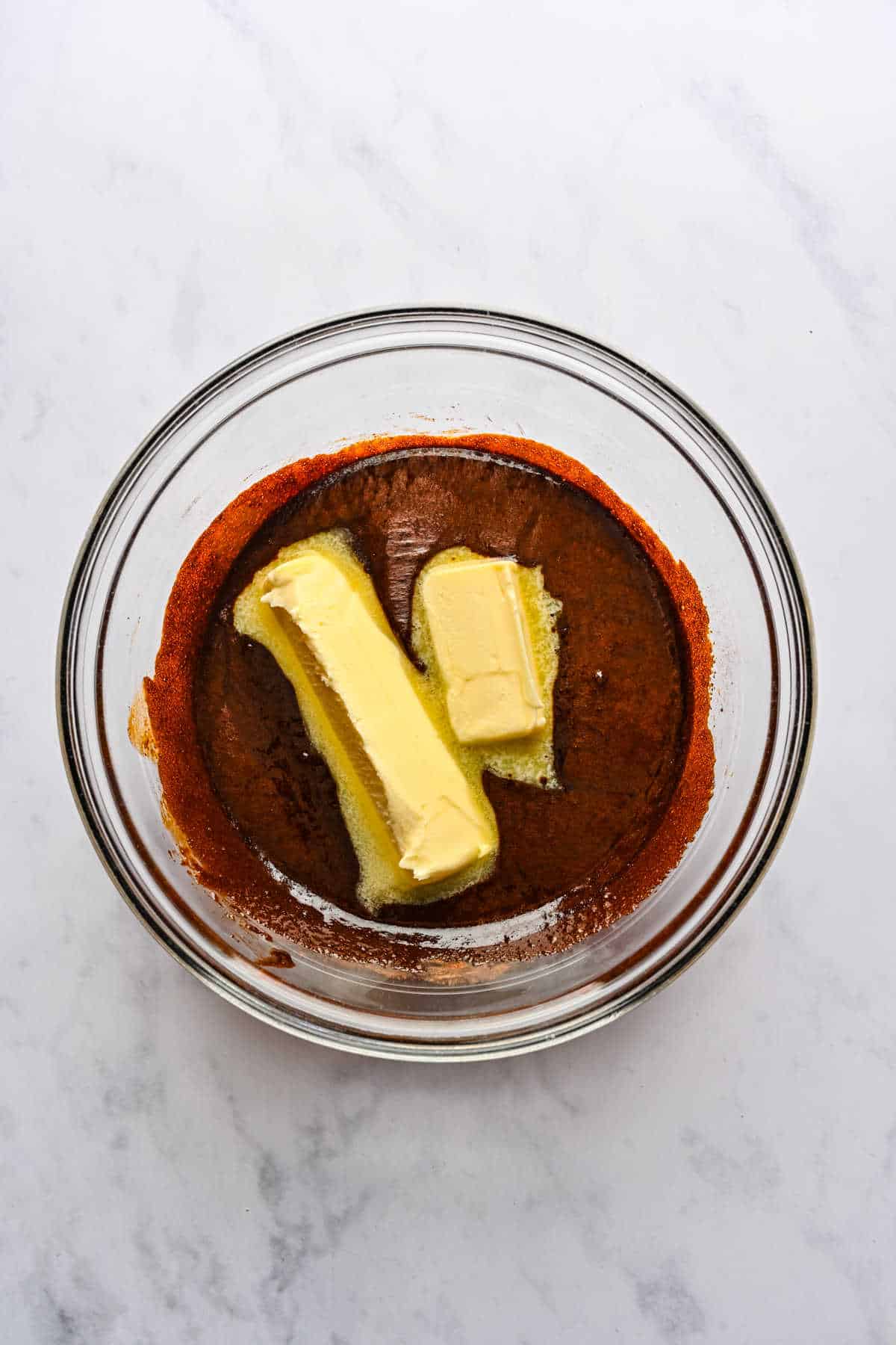 Molasses mixture with two sticks of butter in a glass mixing bowl. 