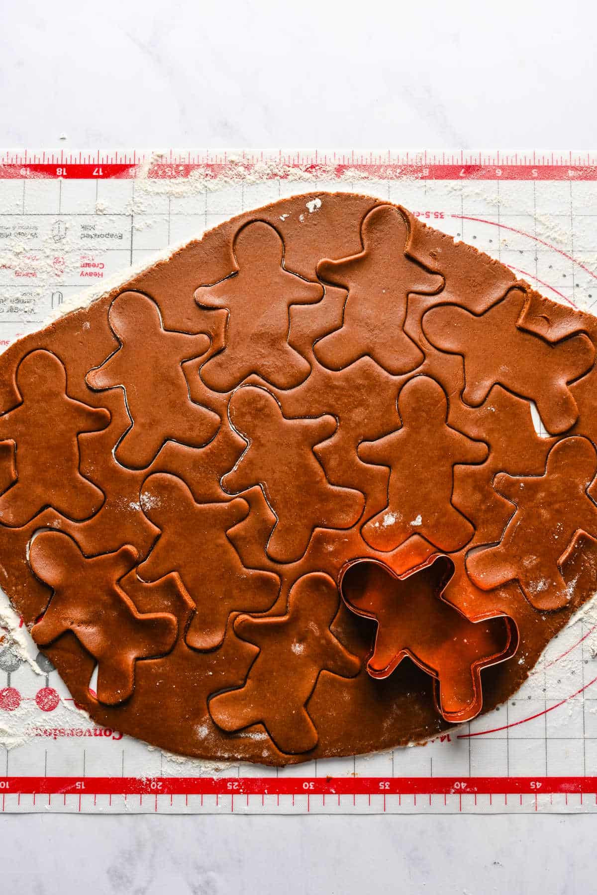 Rolled out gingerbread men dough on a baking mat.