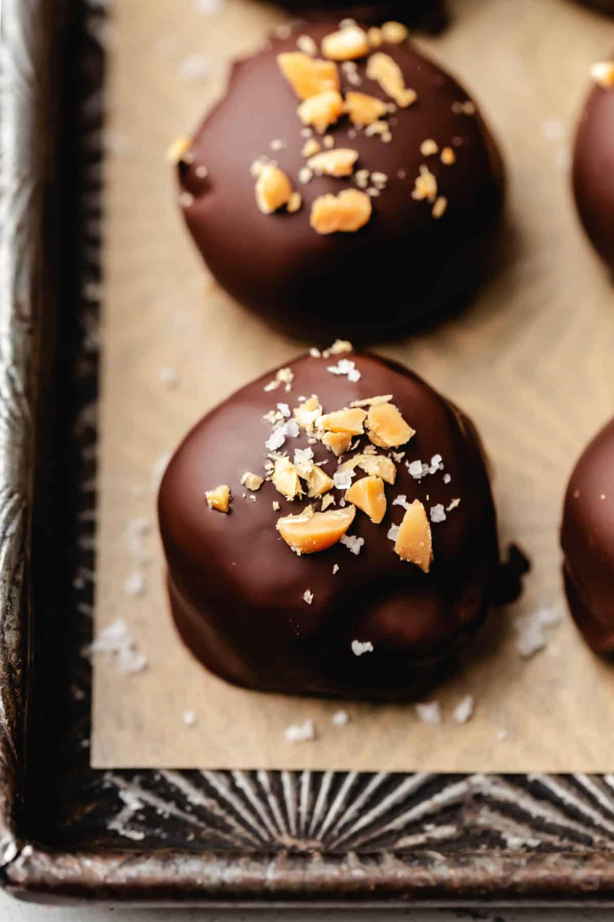 A row of peanut butter Oreo cookie balls topped with salt and chopped peanuts.