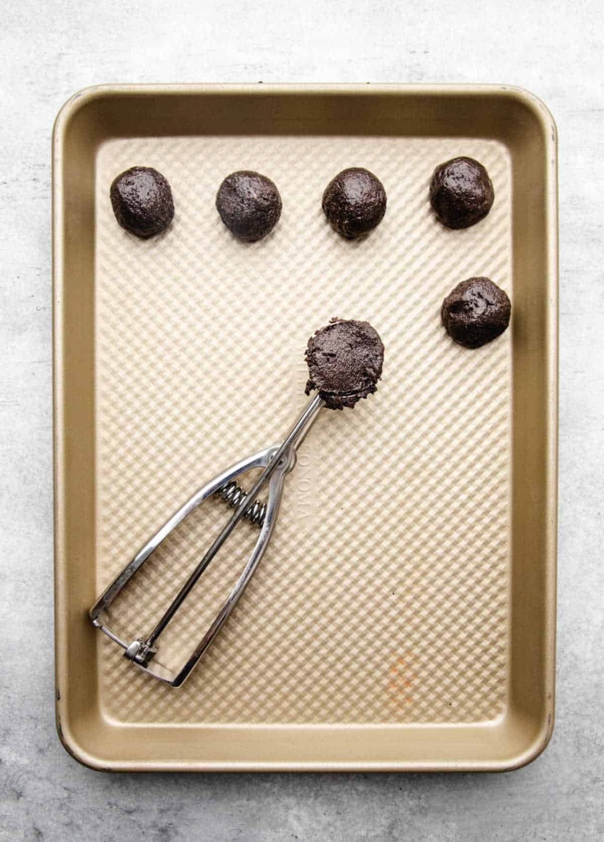 A cookie scoop holding peanut butter Oreo cookie ball mixture. 