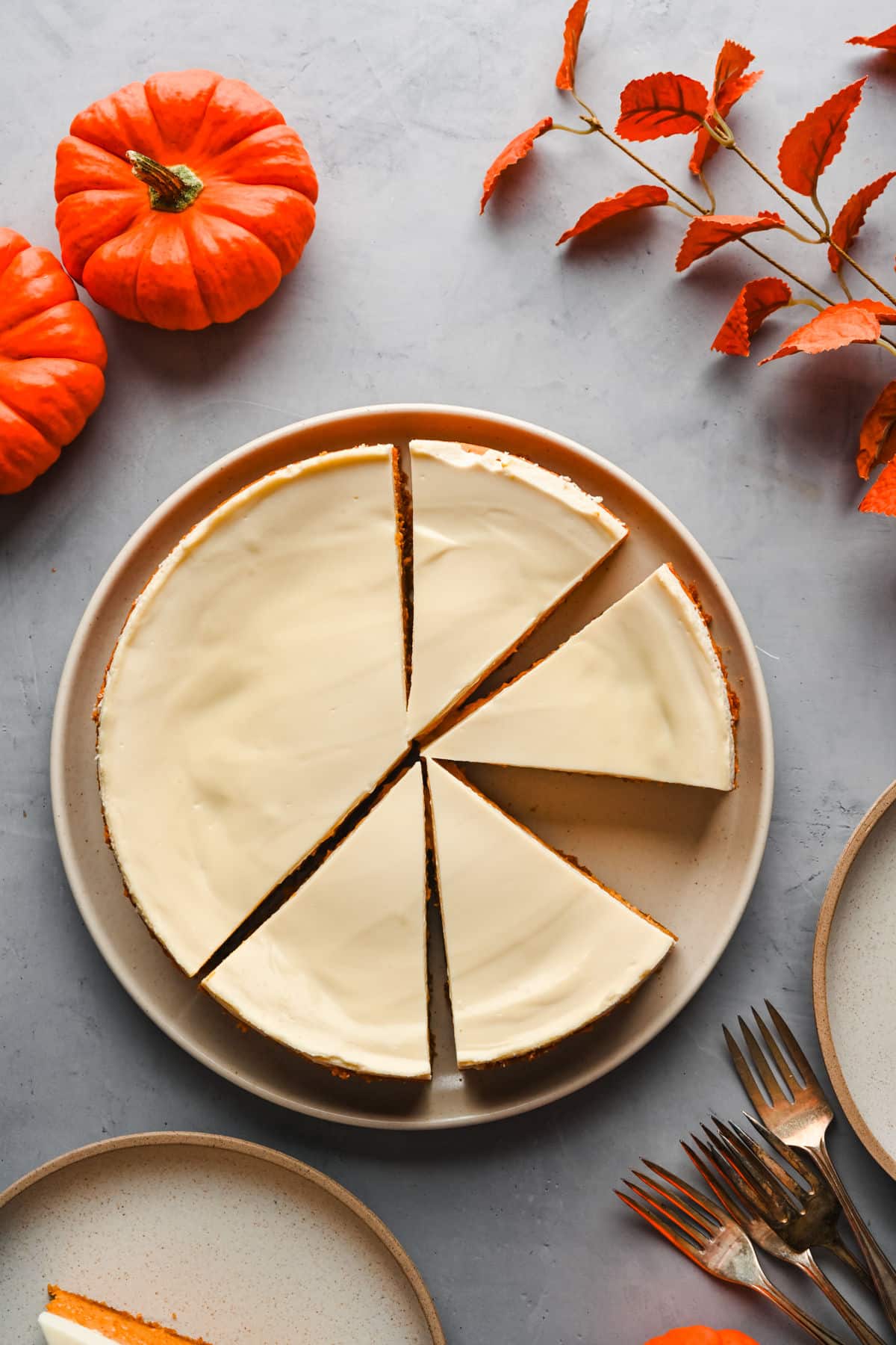 A pumpkin cheesecake with a few slices cut at an angle. 