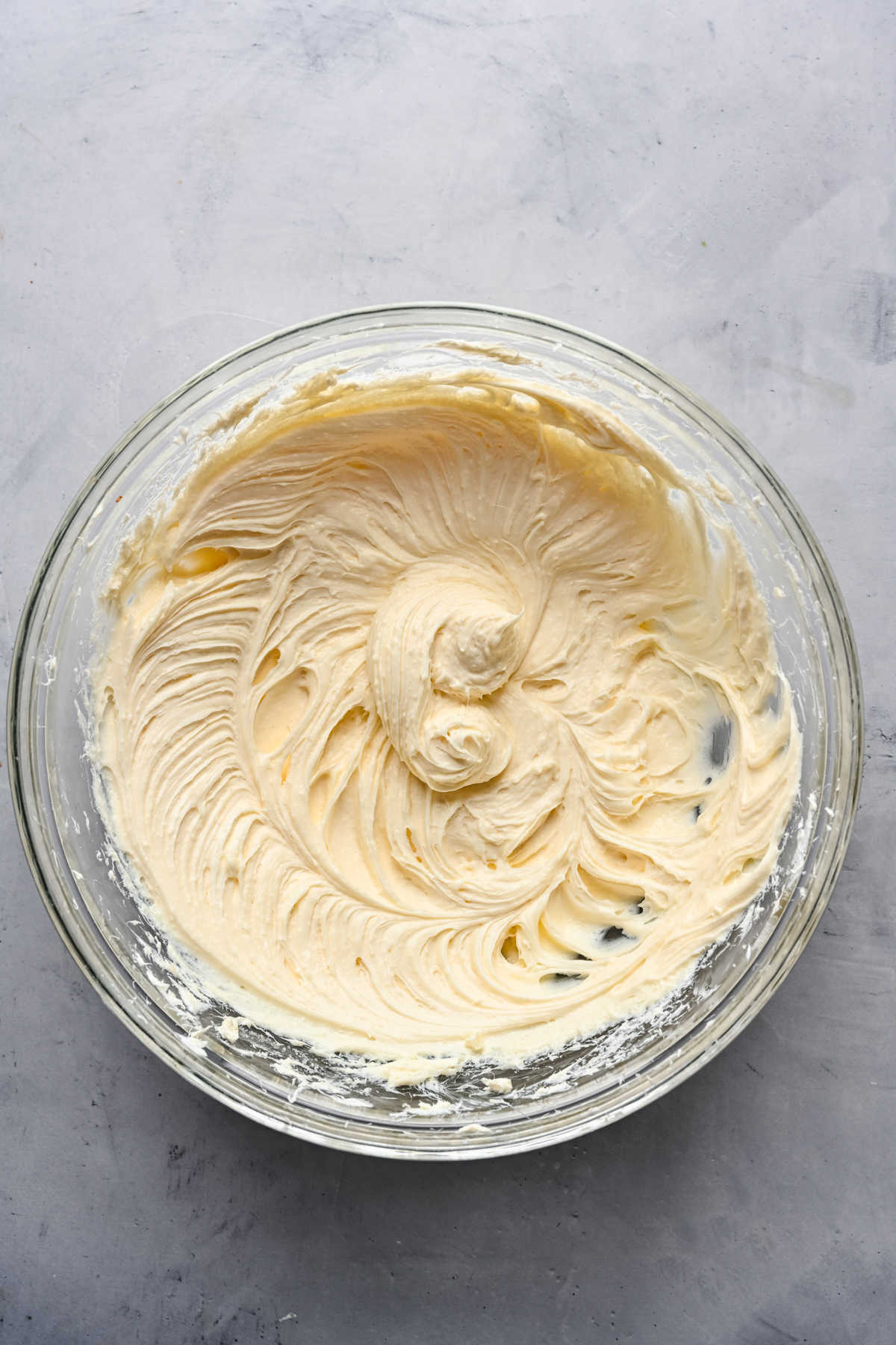 Cream cheese beaten in a glass mixing bowl. 