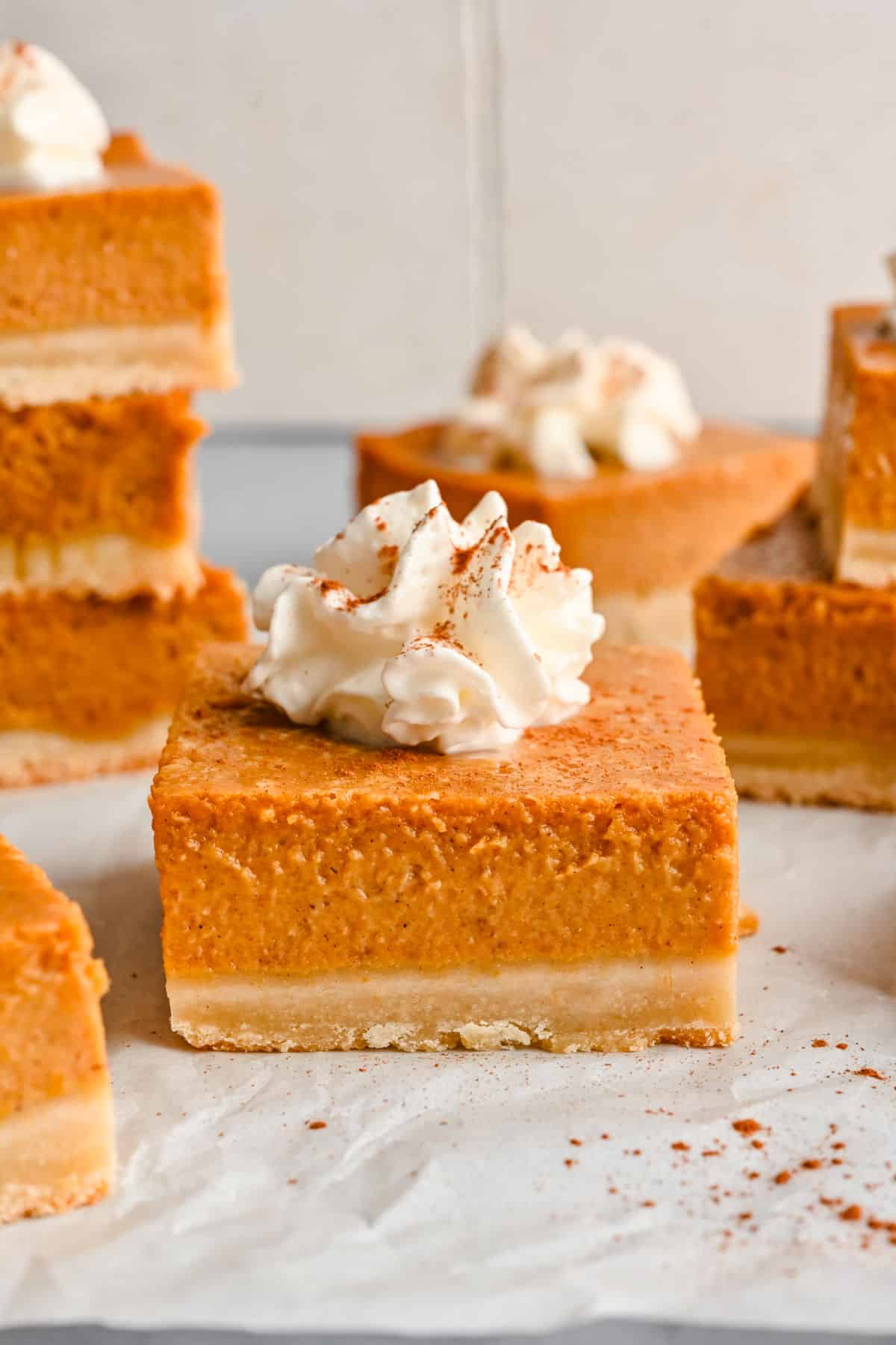 A pumpkin pie bar topped with whipped cream and cinnamon.