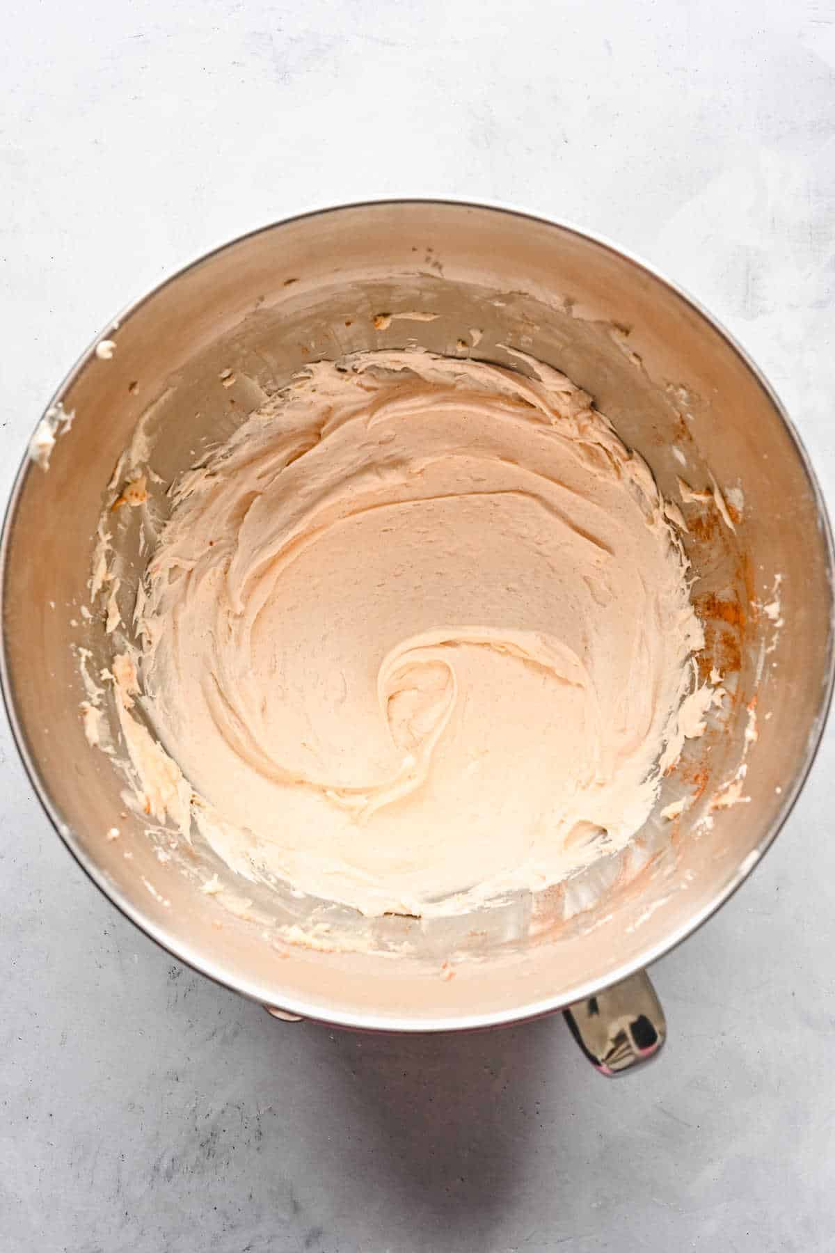 Cream cheese frosting in a silver mixing bowl. 