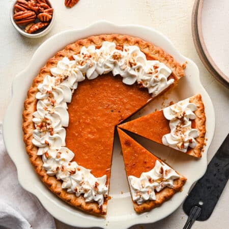 A sweet potato pie with two slices cut on it.