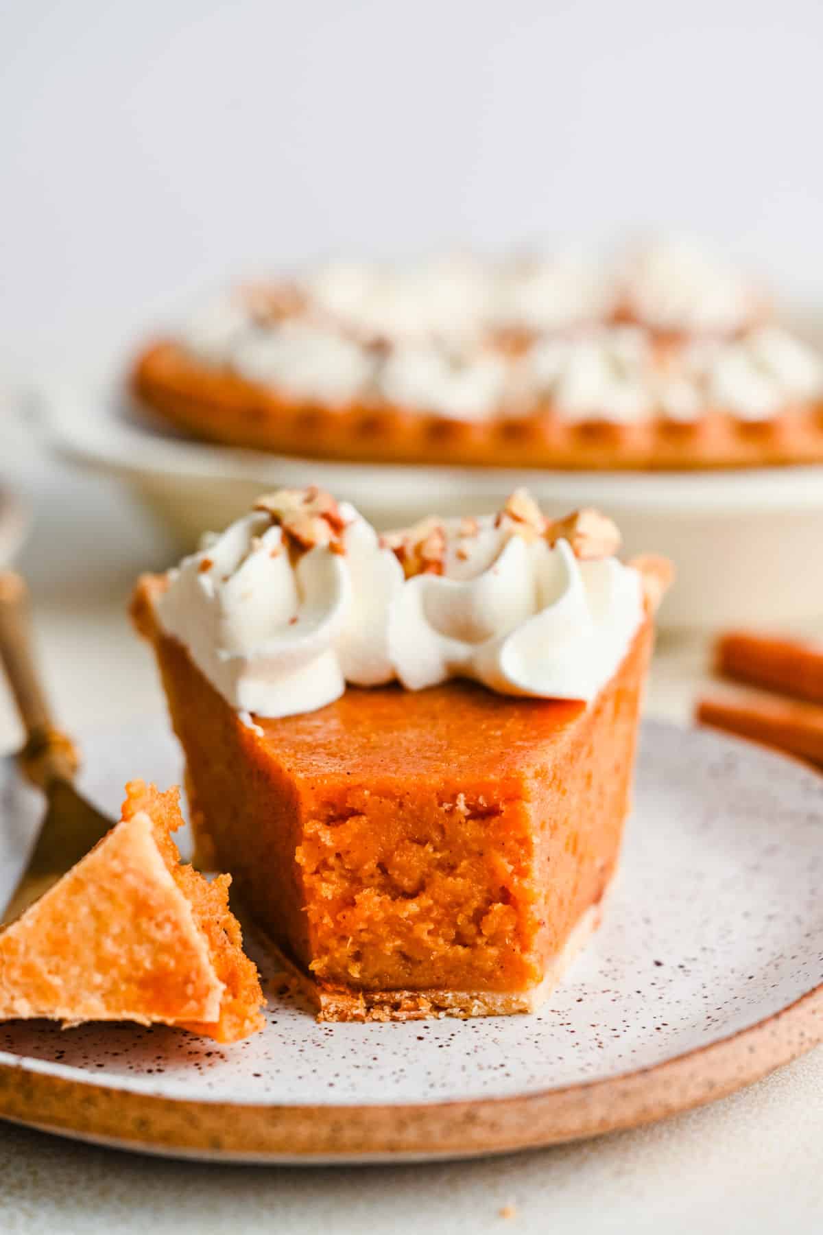 A close up photo of a slice of sweet potato pie with a bite on the fork next to it.