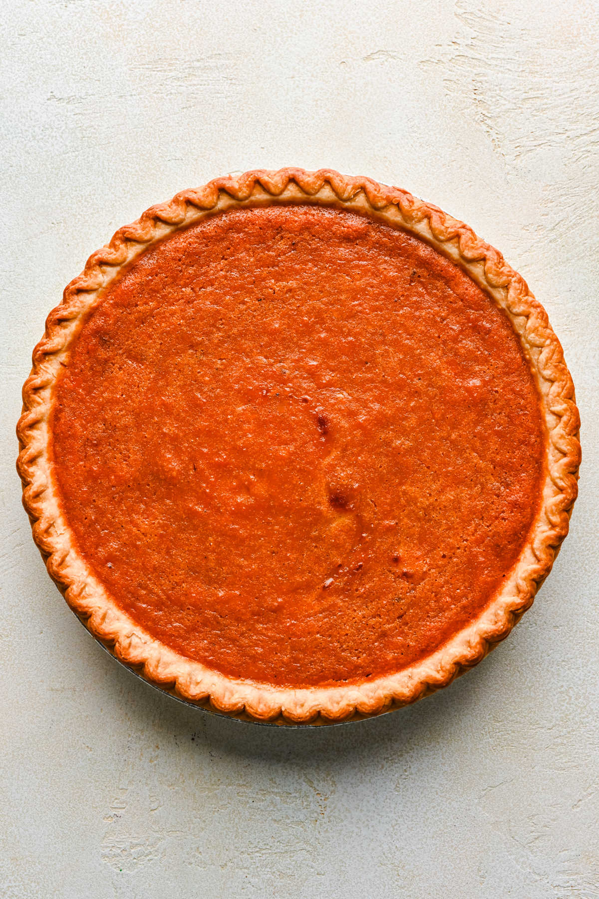 A baked sweet potato pie with a fluted crust. 