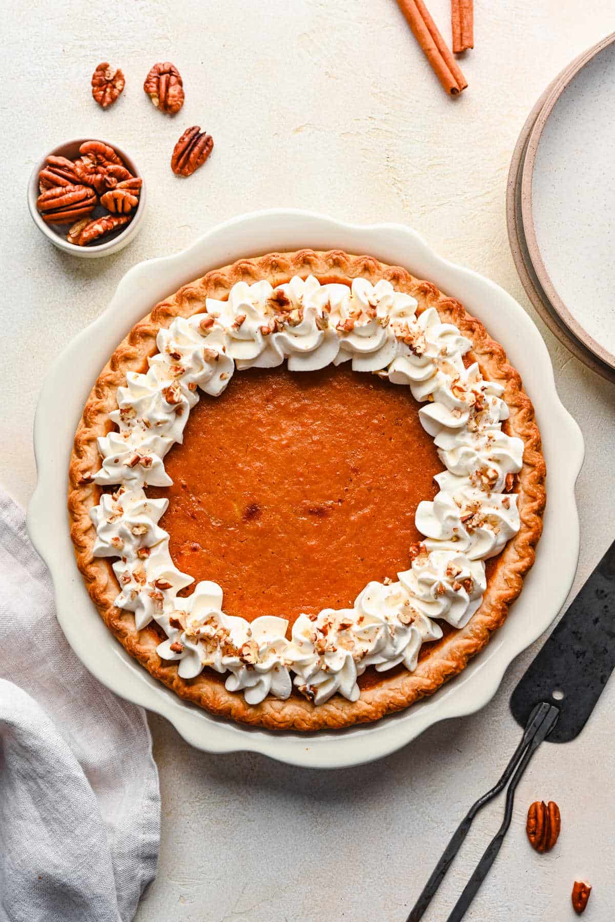 A sweet potato pie topped with whipped cream and pecans.