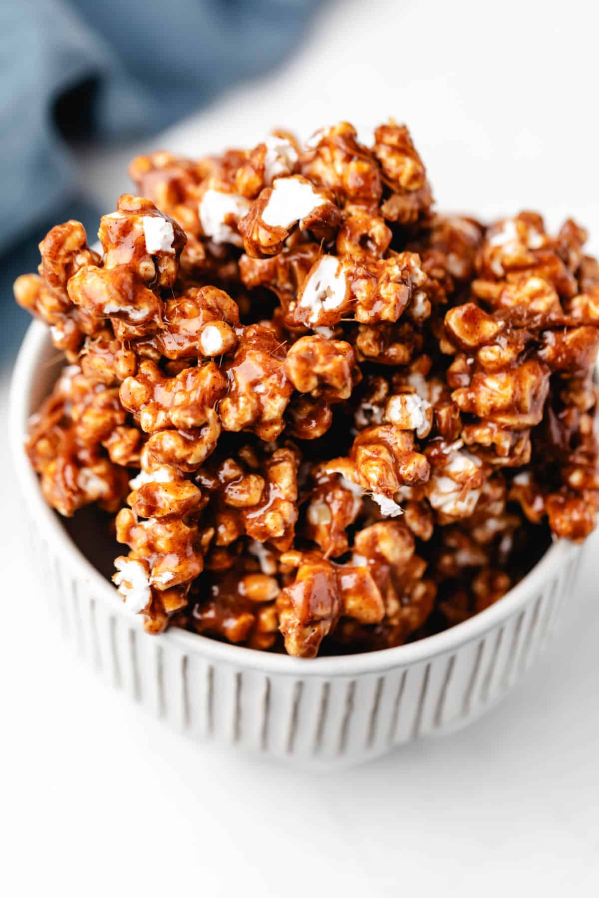 Cinnamon roll popcorn in a white and brown pottery dish. 