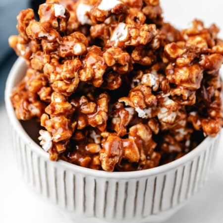 Cinnamon bun popcorn in a white dish next to a blue kitchen linen.