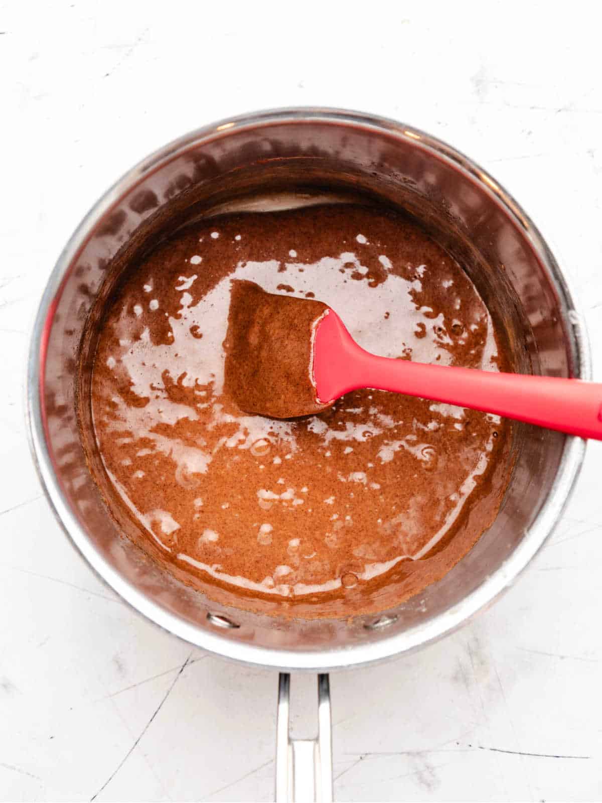 Cinnamon and marshmallows stirred into corn syrup mixture in a saucepan.