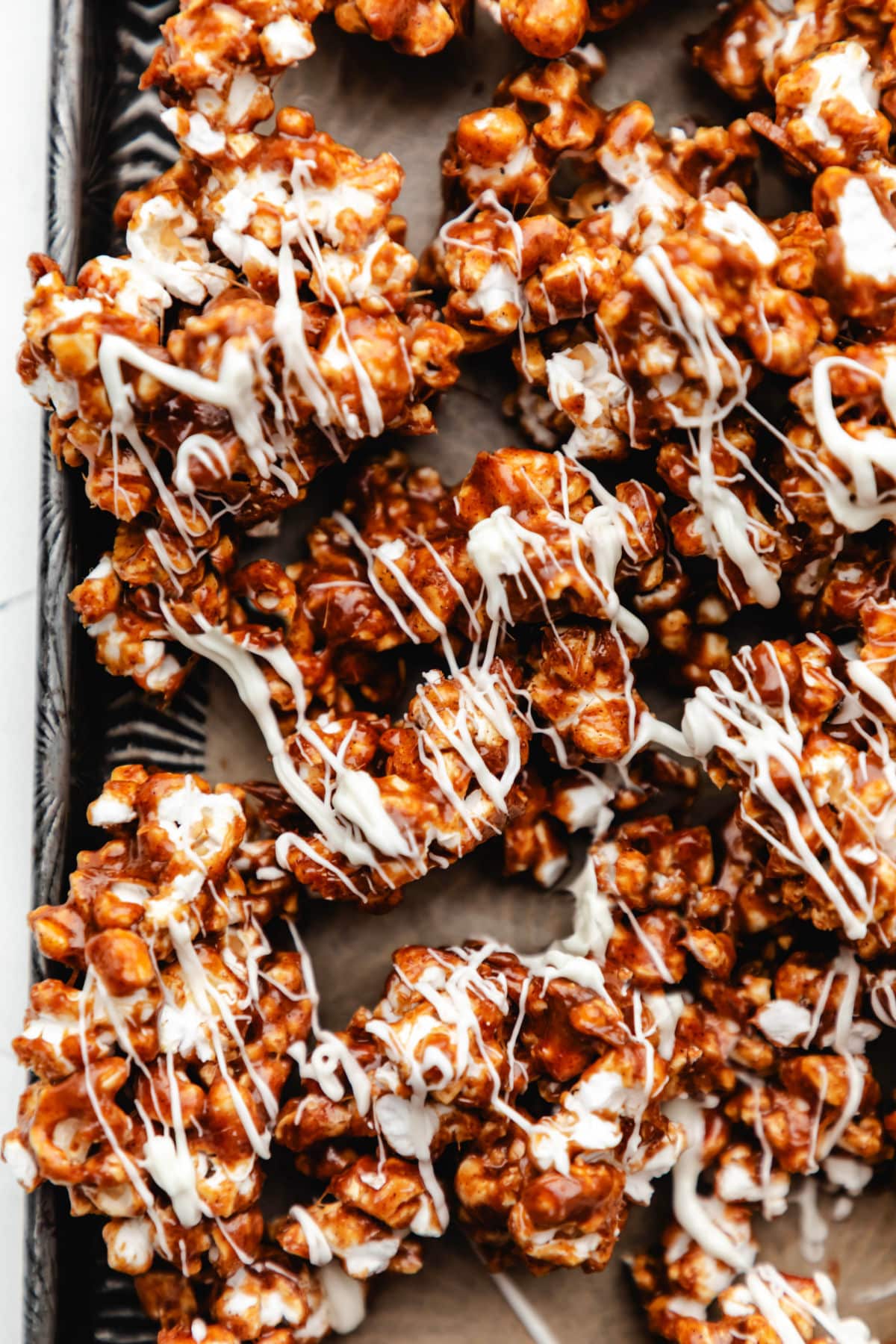 White chocolate drizzled over cinnamon roll popcorn on a baking sheet. 