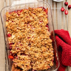 A wooden spoon scooping out cranberry apple crisp from the dish.