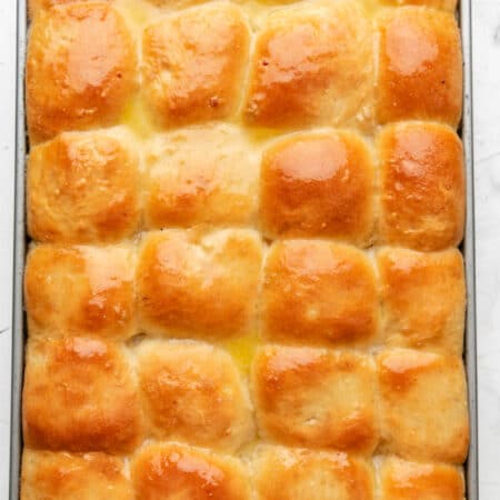 A pan of baked potato rolls brushed with melted butter.