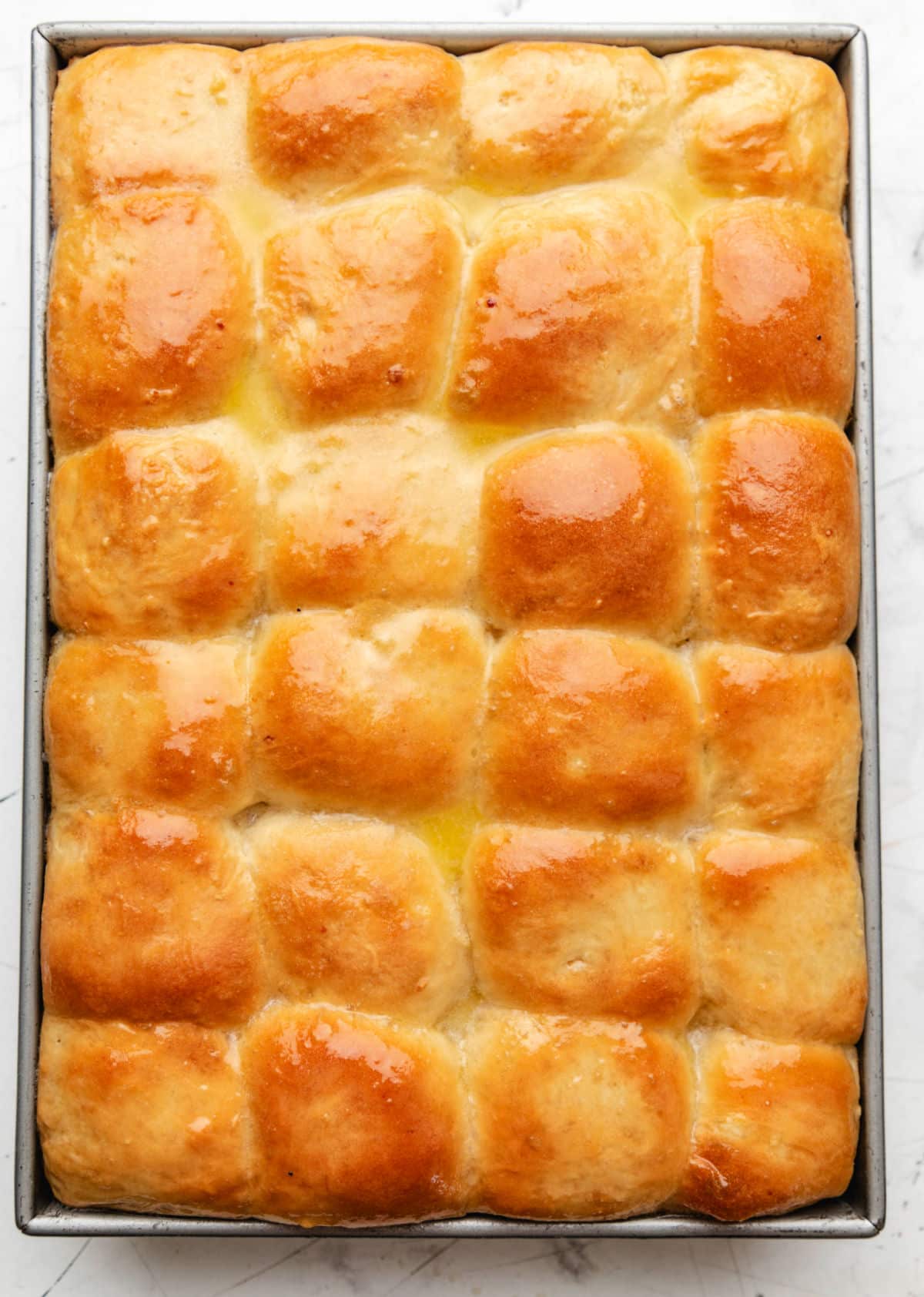 A pan of baked potato rolls brushed with melted butter. 