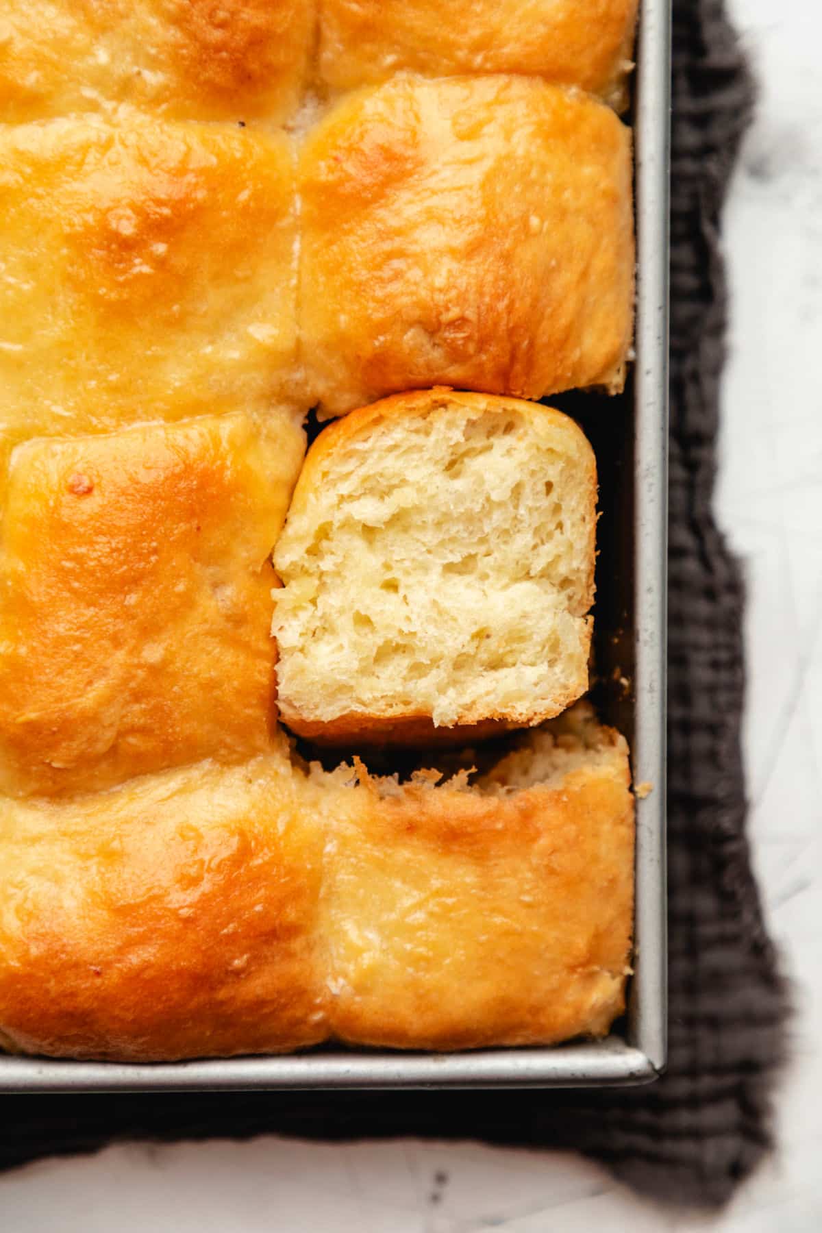 A pan of potato rolls on a dark gray linen.