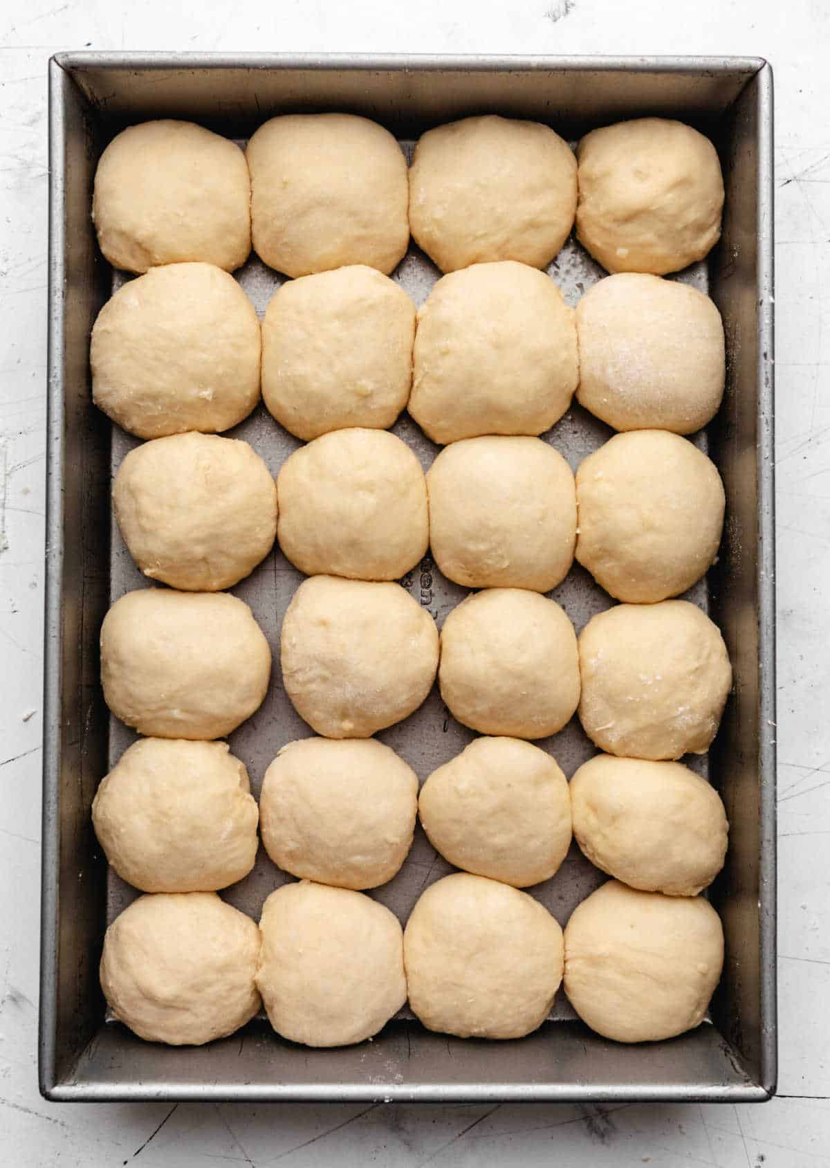 Potato roll dough in a silver baking pan.