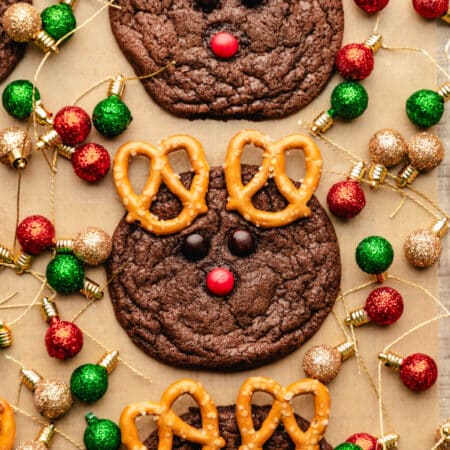 Three reindeer cookies on surrounded by Christmas light ornaments.