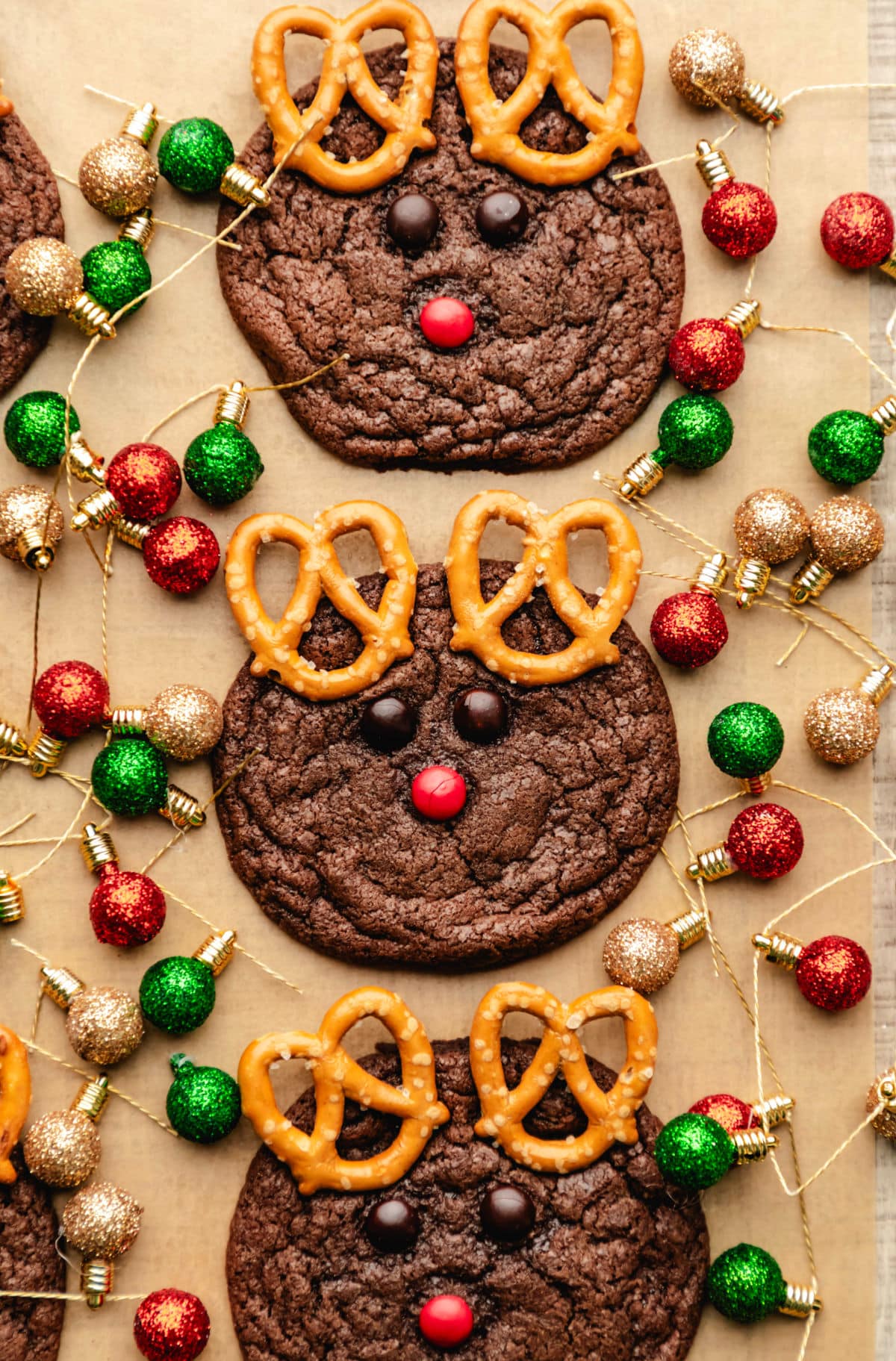 Reindeer Cookie Recipe Three reindeer cookies on surrounded by Christmas light ornaments.