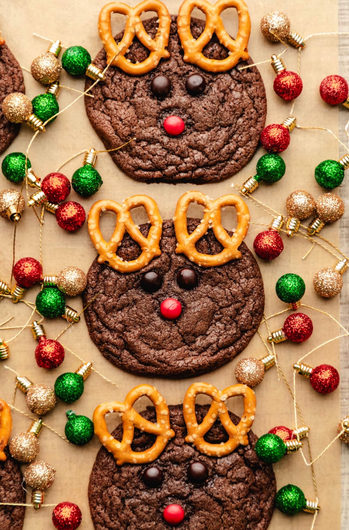 Three reindeer cookies on surrounded by Christmas light ornaments.