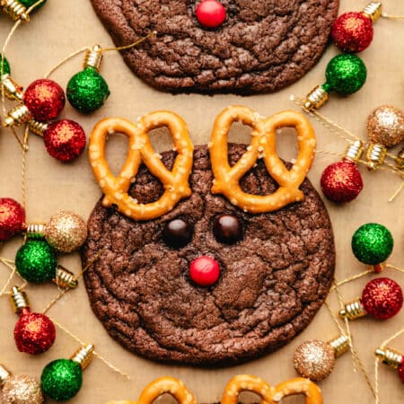Three reindeer cookies surrounded by Christmas light ornaments.