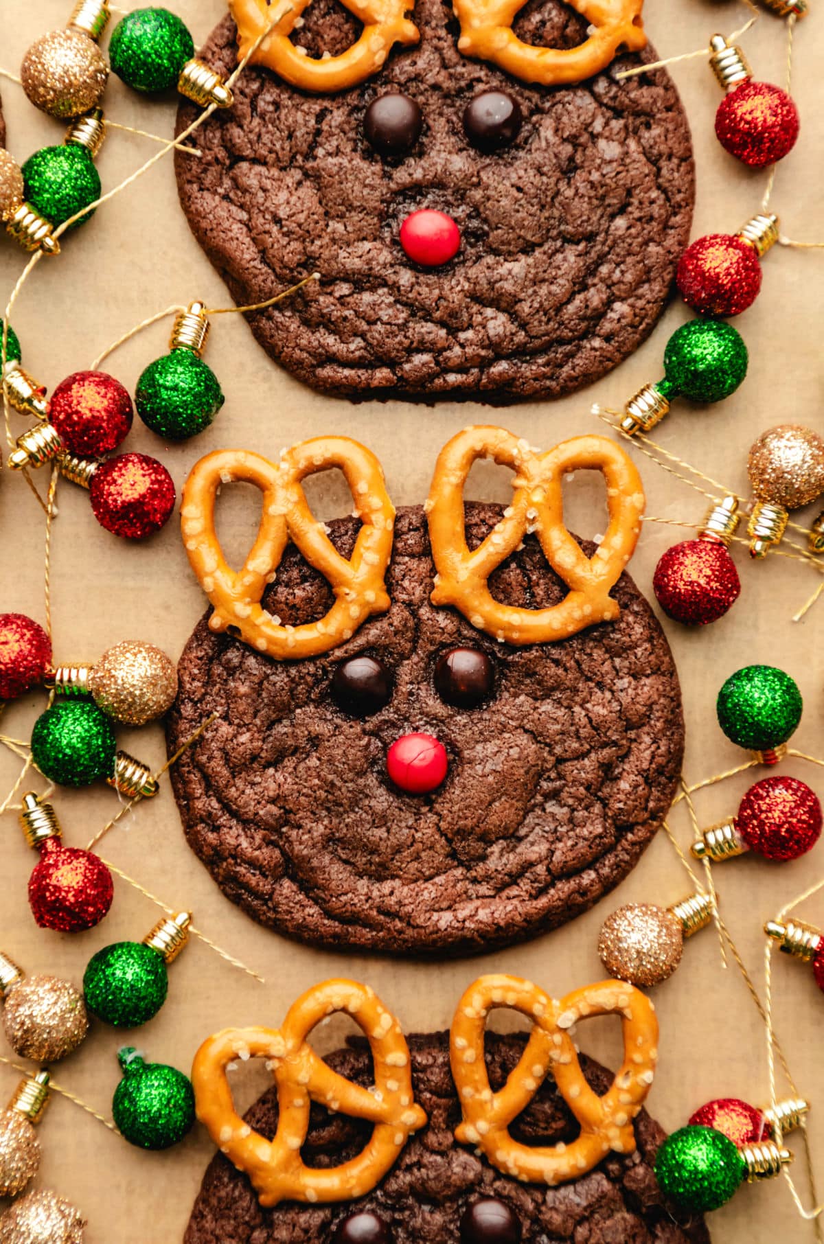 Three reindeer cookies surrounded by Christmas light ornaments.
