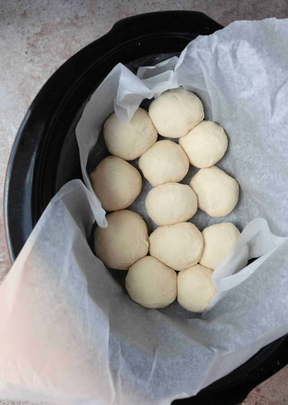 Unrisen slow cooker dinner roll dough in a slow cooker. 