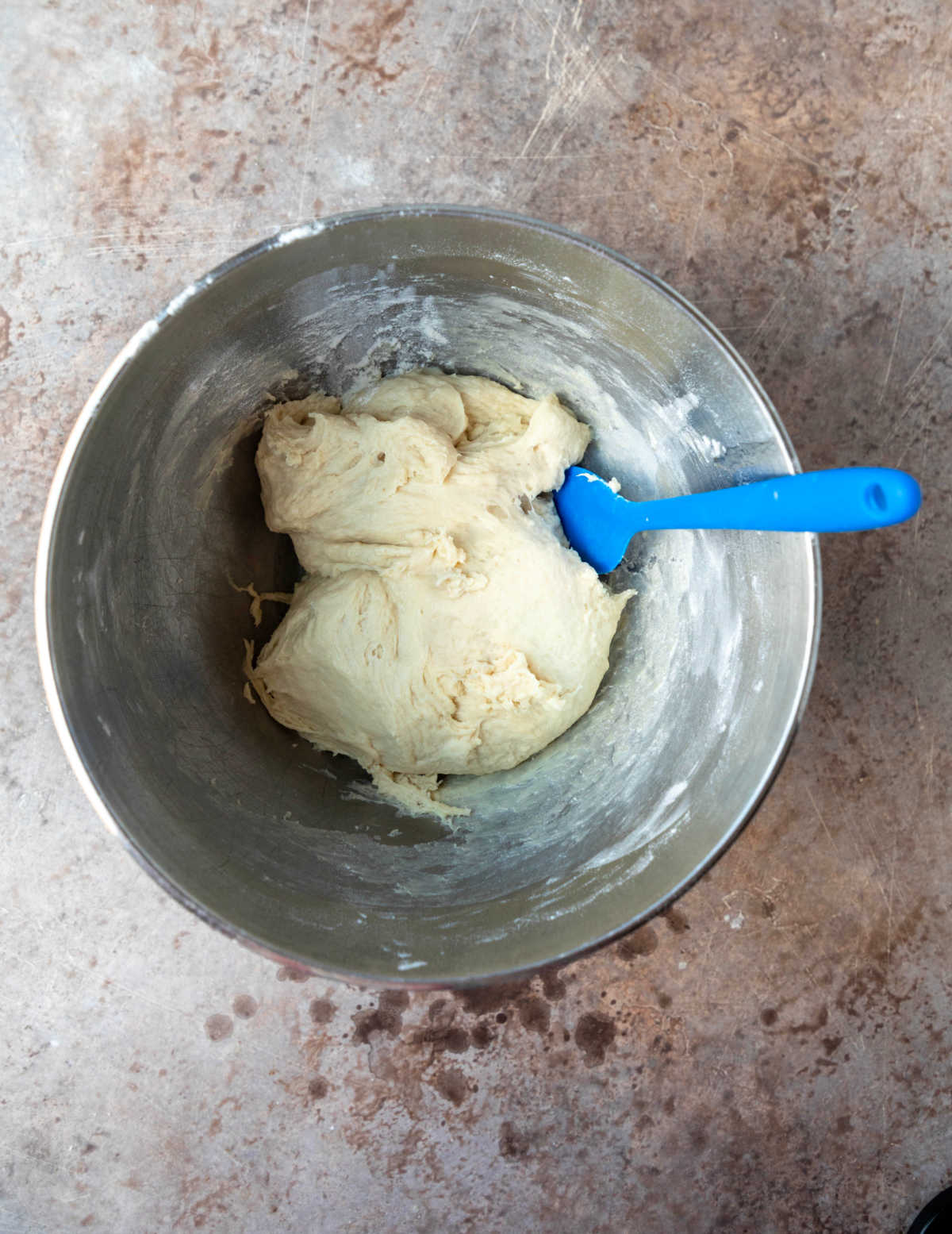 Slow cooker dinner roll dough in a silver mixing bowl. 