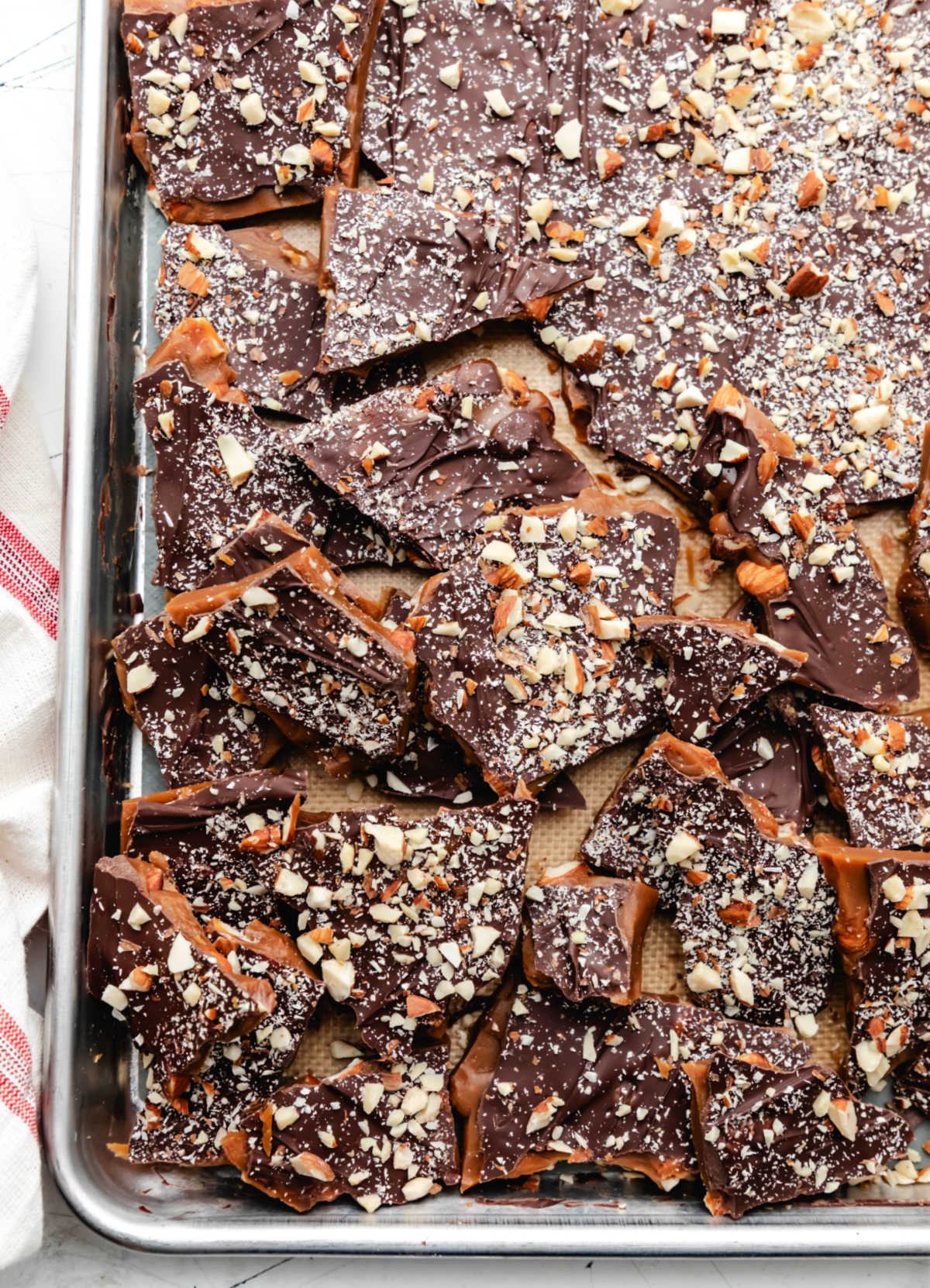 Cooled toffee broken into pieces in a baking pan.