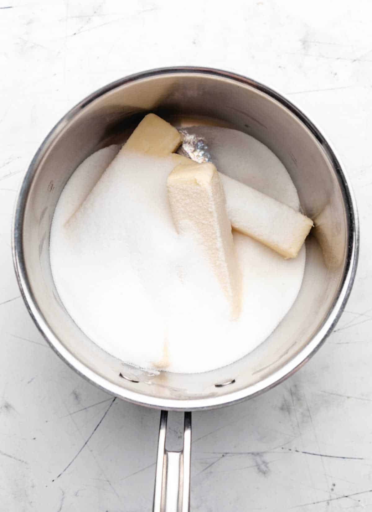 Sticks of butter and granulated sugar in a saucepan.