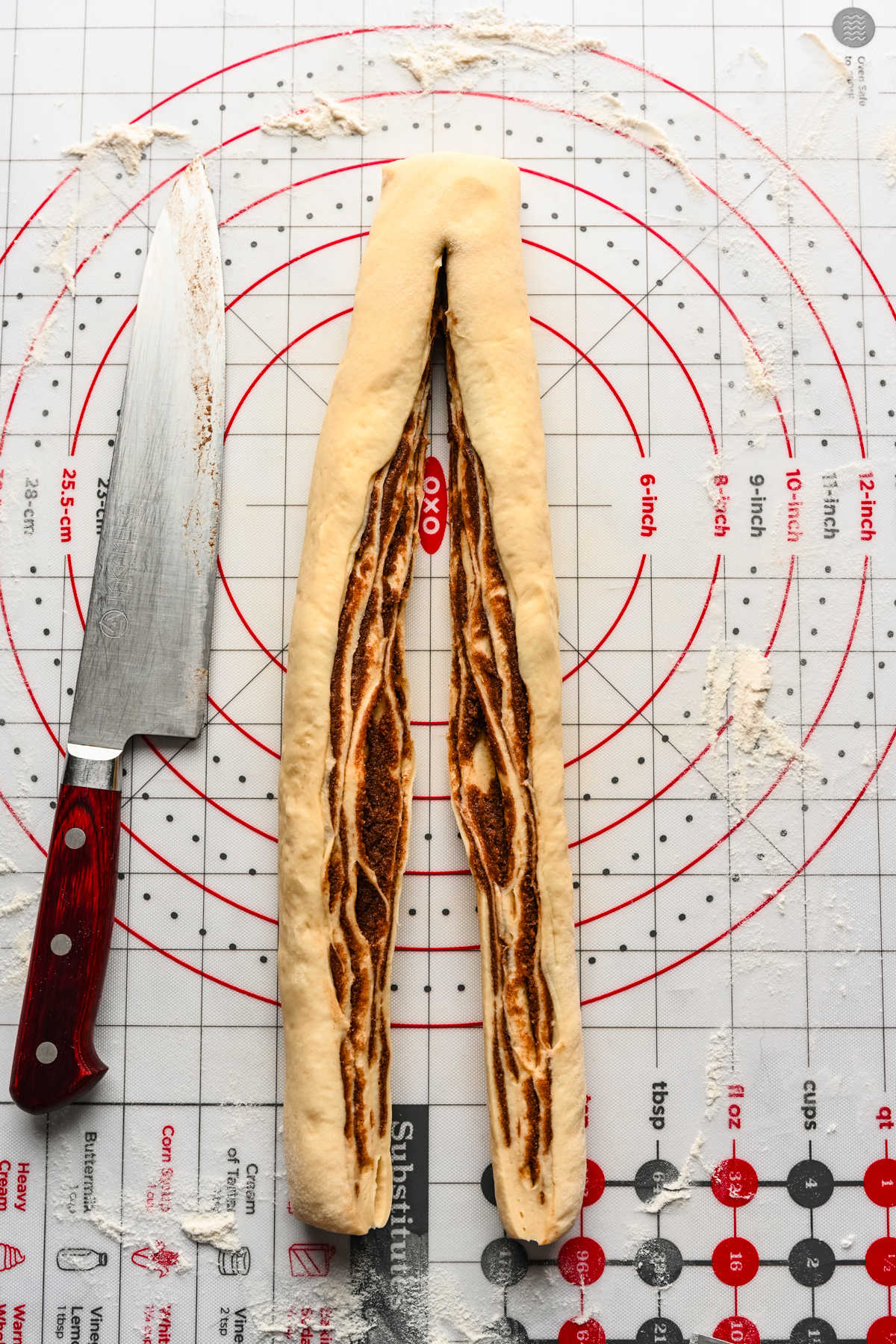 A rolled up section of cinnamon bread dough cut down the middle.