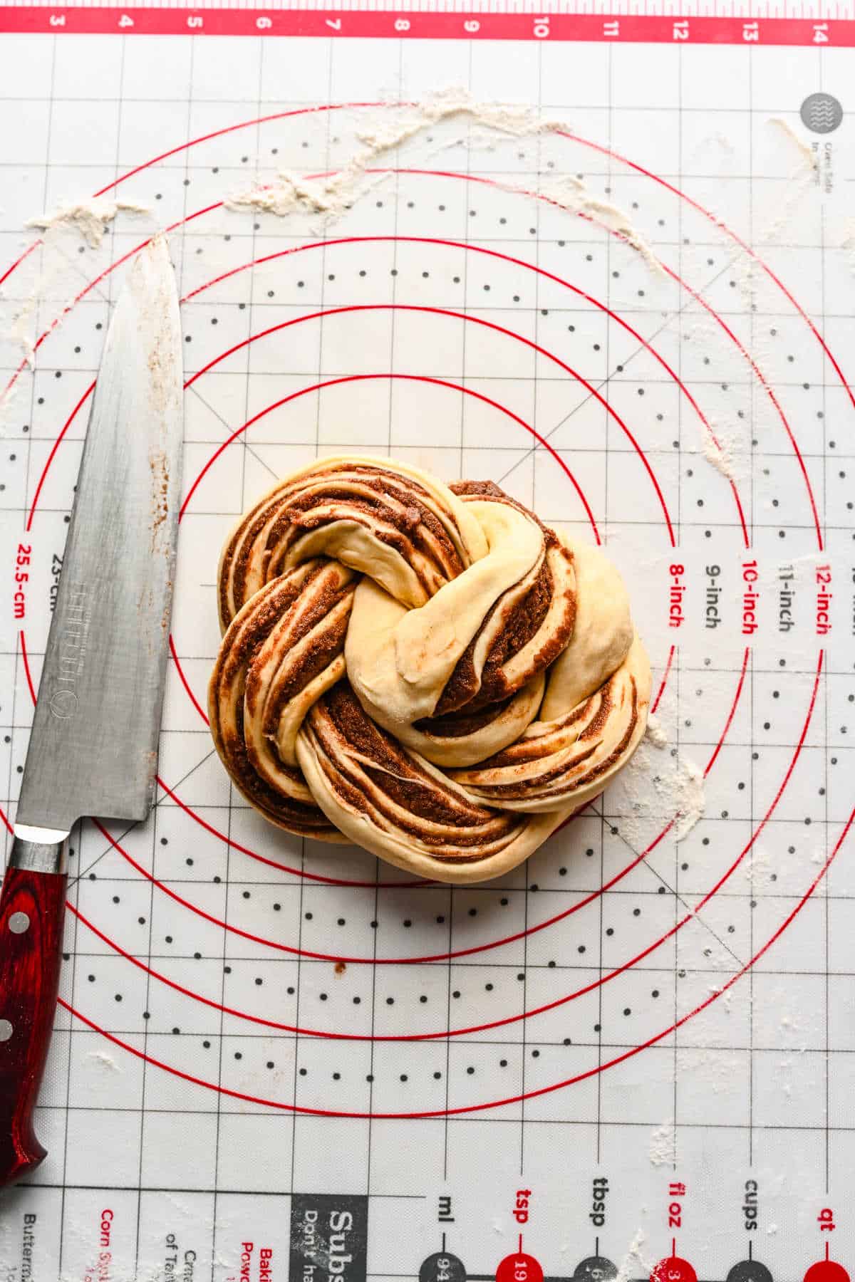 Braided cinnamon bread dough in a coil on a baking mat. 