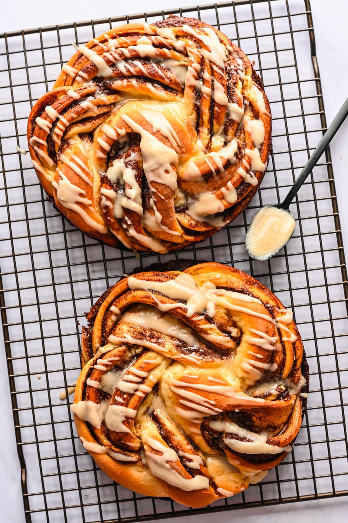Two loaves of braided cinnamon bread on a wire cooling rack. 