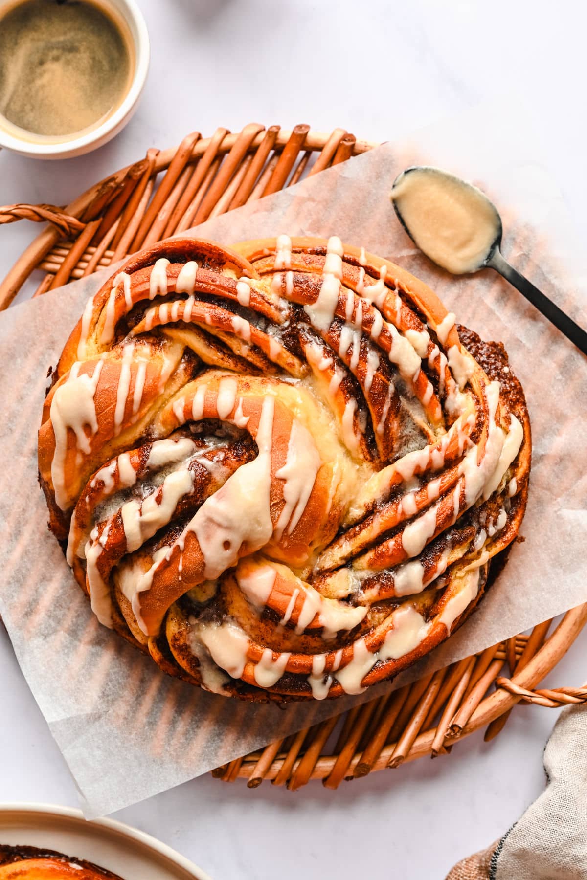 A loaf of braided cinnamon bread on a parchment lined wicker platter. 