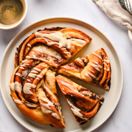 A loaf of braided cinnamon bread with two pieces cut.