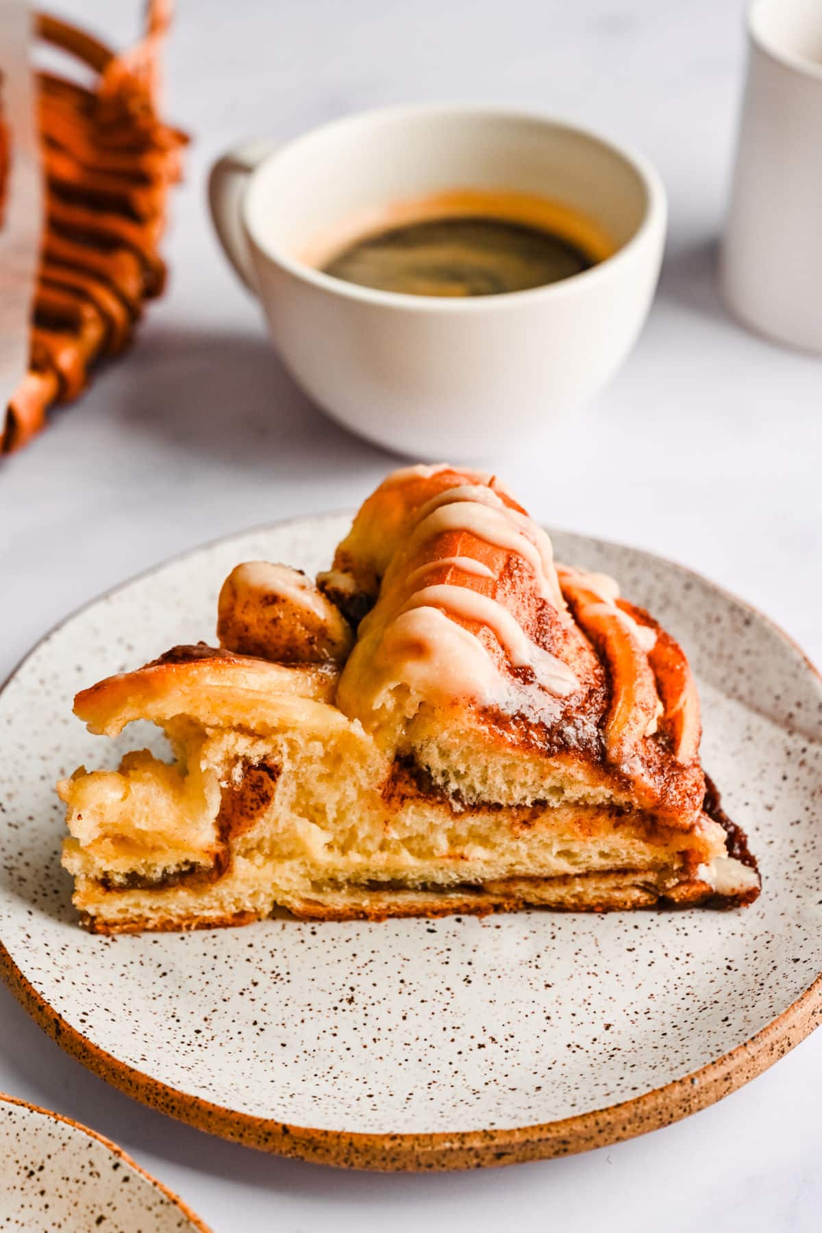 A slice of braided cinnamon bread on a speckled plate. 