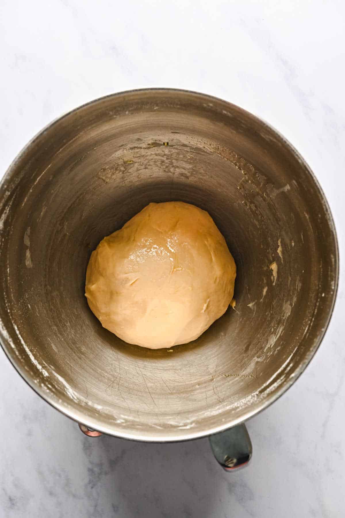 Dough coated in oil in a silver mixing bowl. 