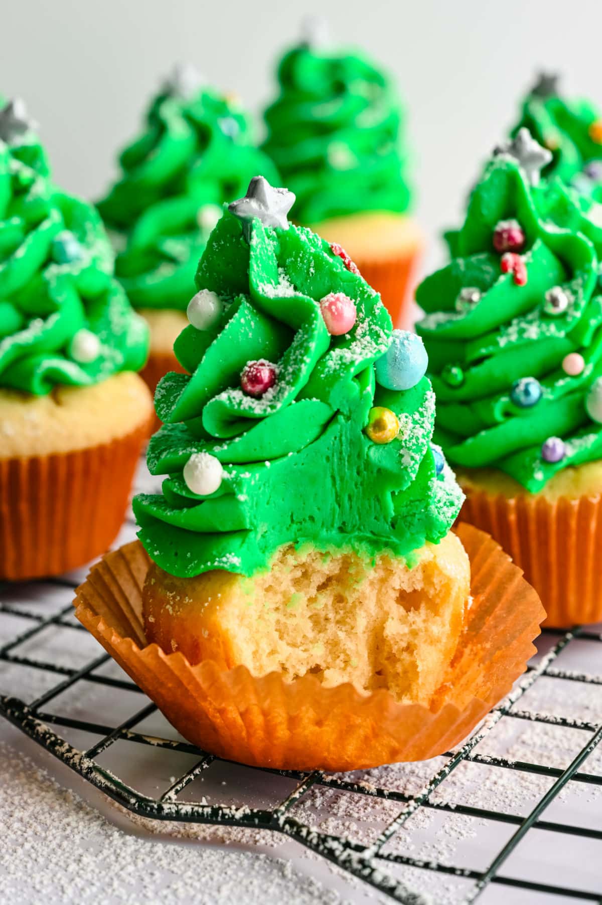 A Christmas tree cupcake with a bite taken out of it. 